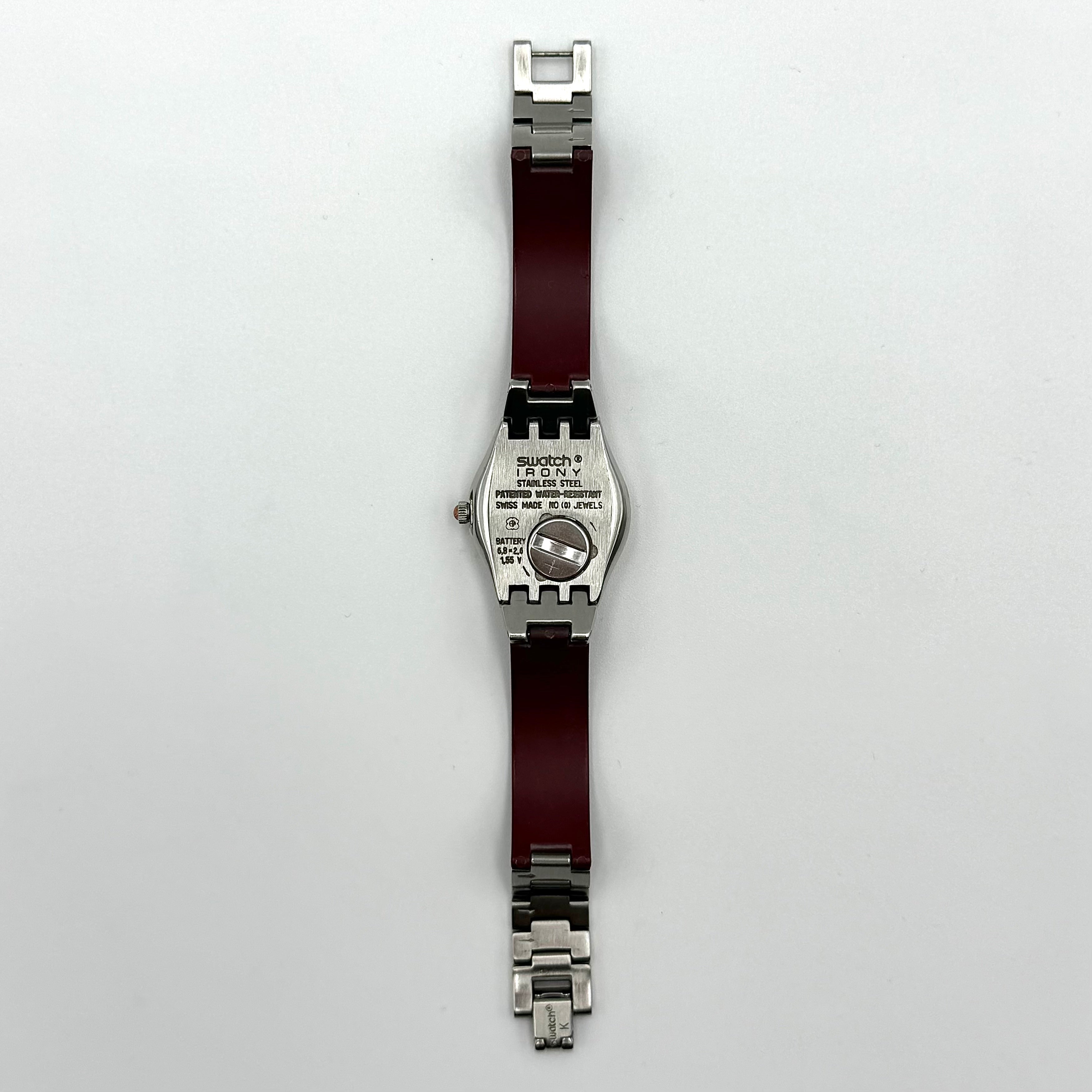 Swatch Irony Lady Angels Call watch in burgundy and silver, presented on a black cushion.
