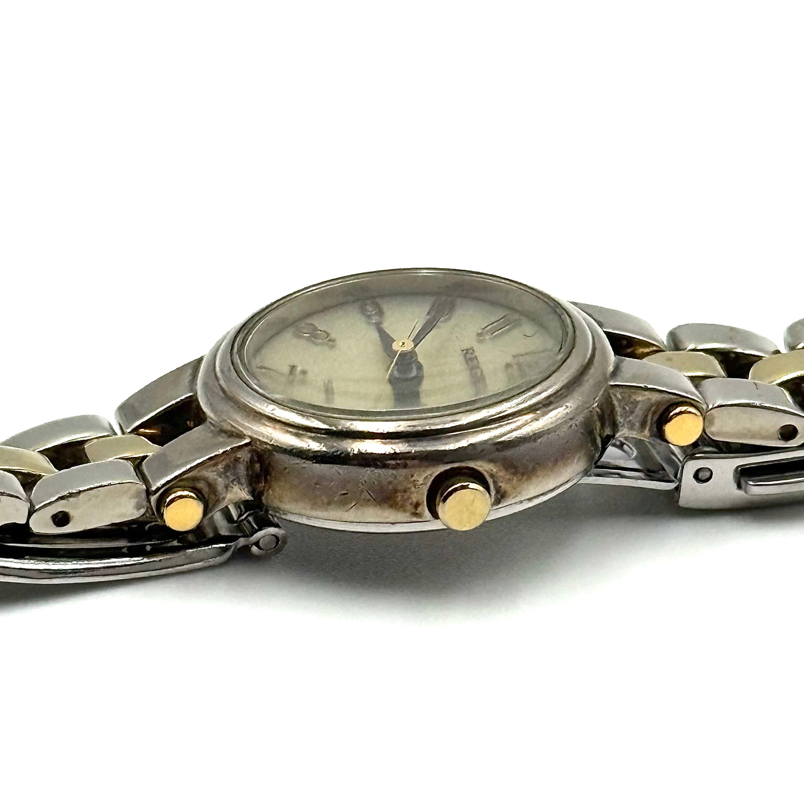 Citizen Reguno two-tone stainless steel watch in gold and silver with a round dial and linked bracelet, displayed on a black pillow.
