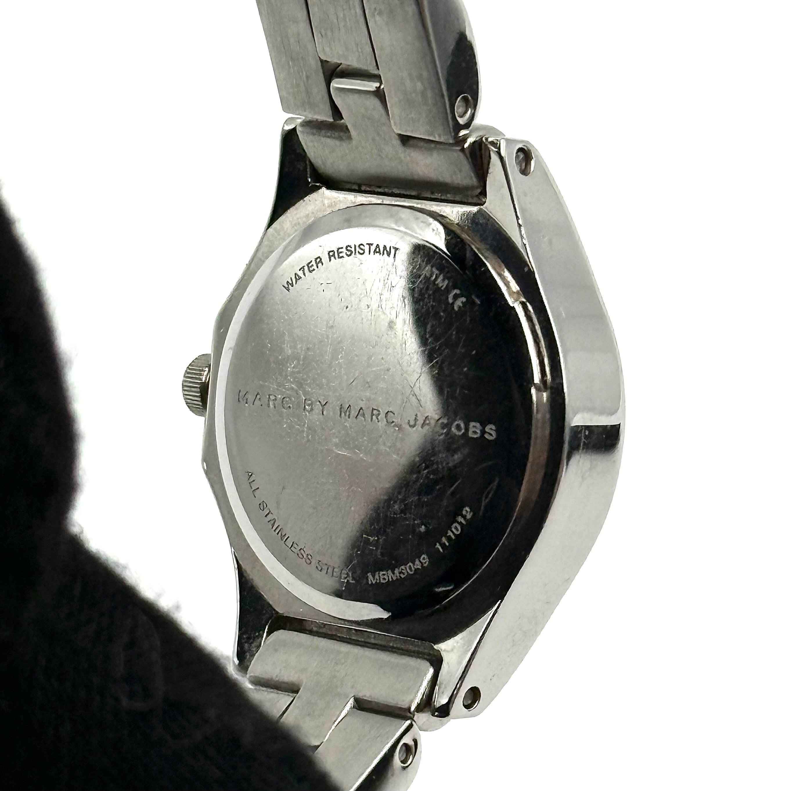 Marc Jacobs Blade MBM3049 watch in stainless steel with a cream bezel, shown on a black cushion.