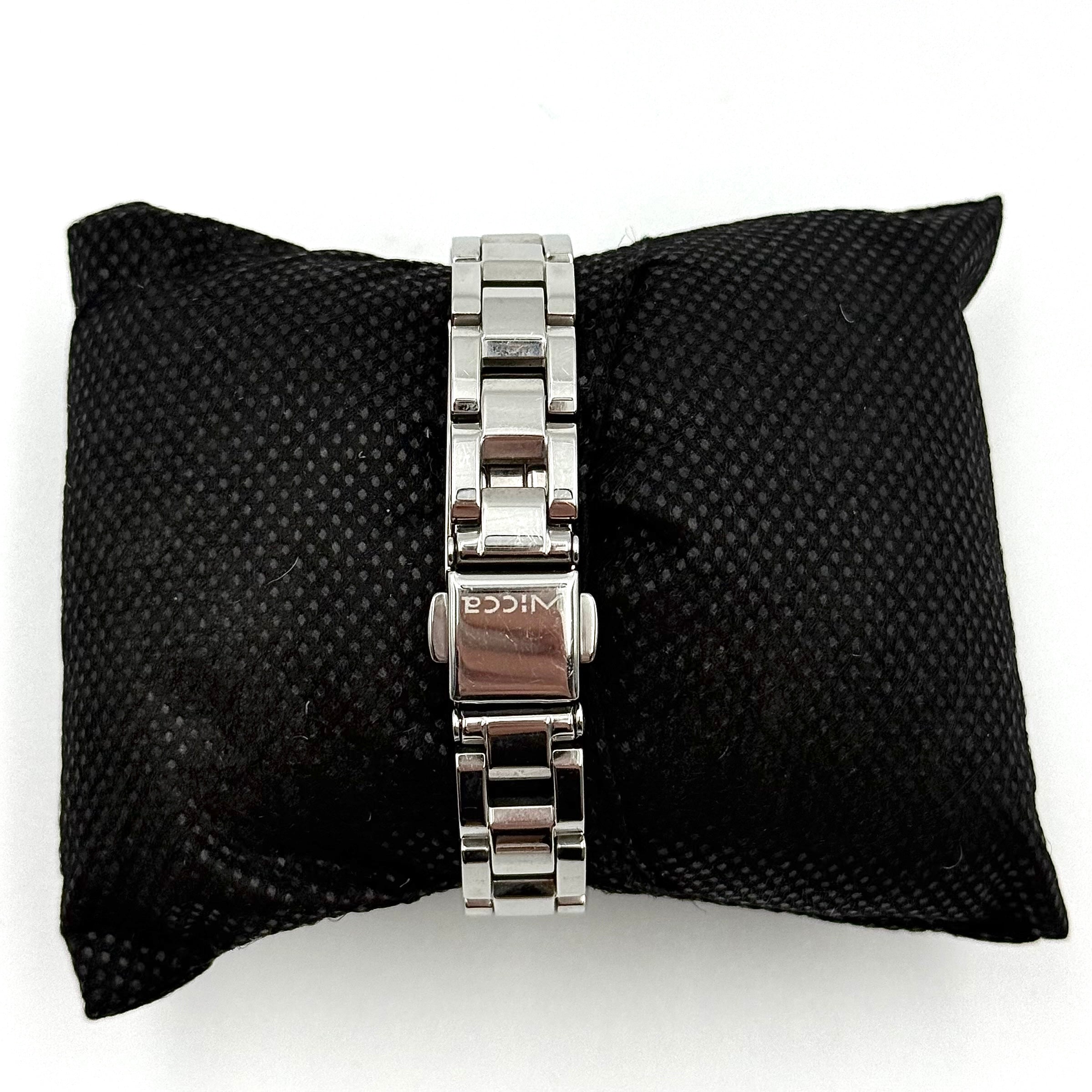 Citizen Wicca stainless steel watch with pink dial and star-detailed bezel shown on a black cushion.