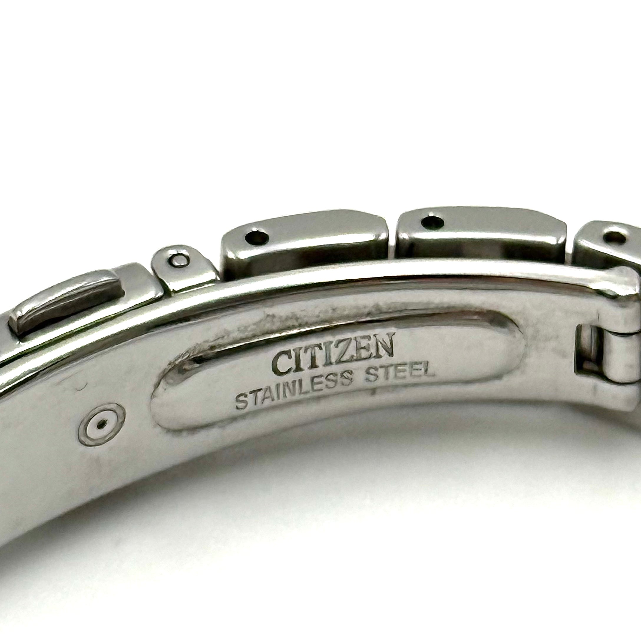 Citizen Wicca stainless steel watch with pink dial and star-detailed bezel shown on a black cushion.