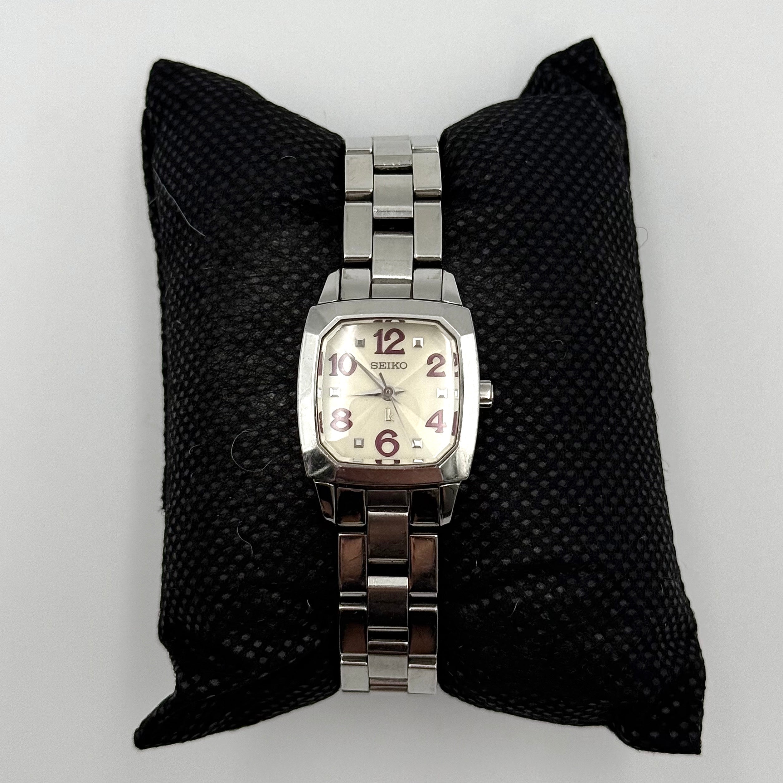 Seiko Lukia stainless steel watch with a rectangular case and silver dial presented on a cushion.