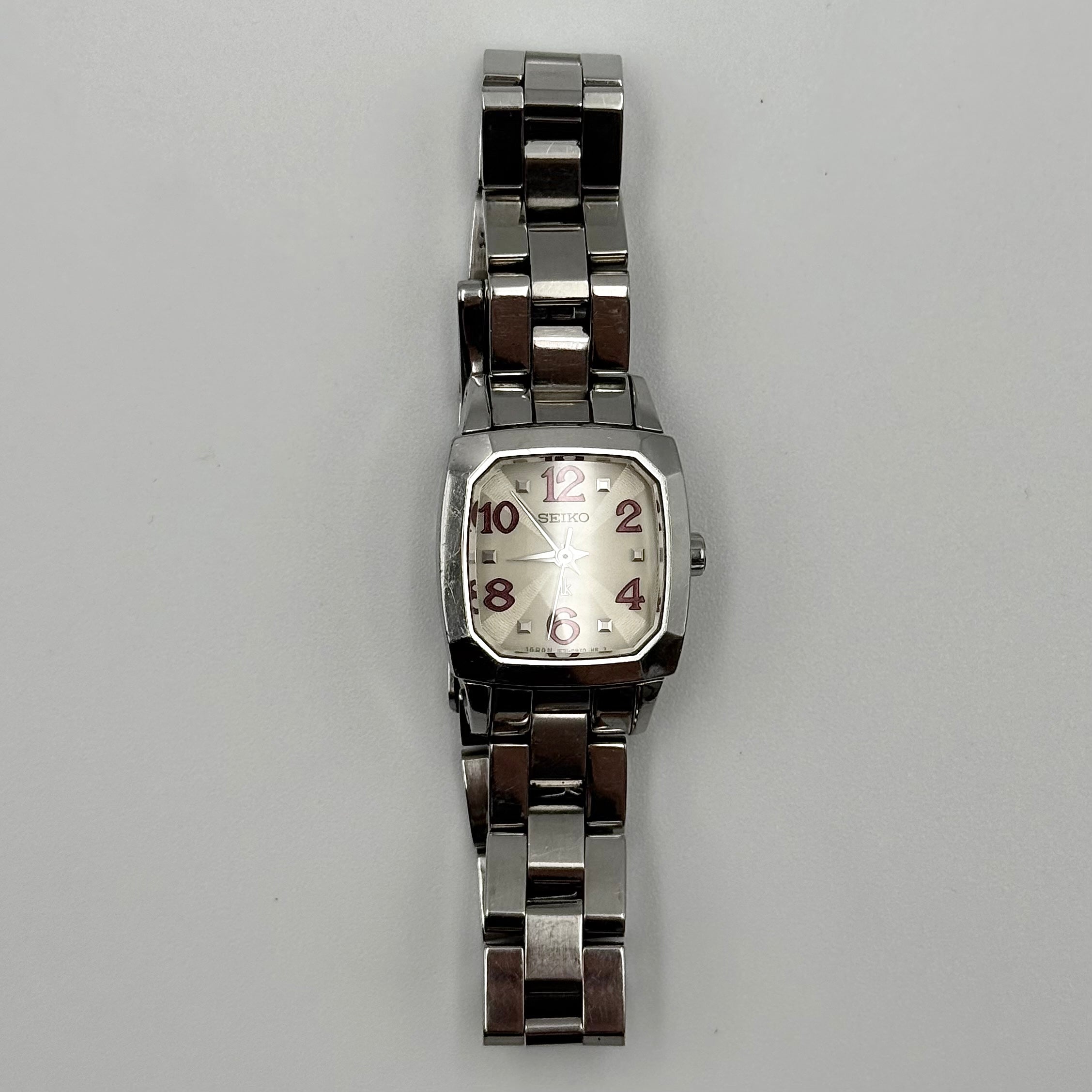 Seiko Lukia stainless steel watch with a rectangular case and silver dial presented on a cushion.