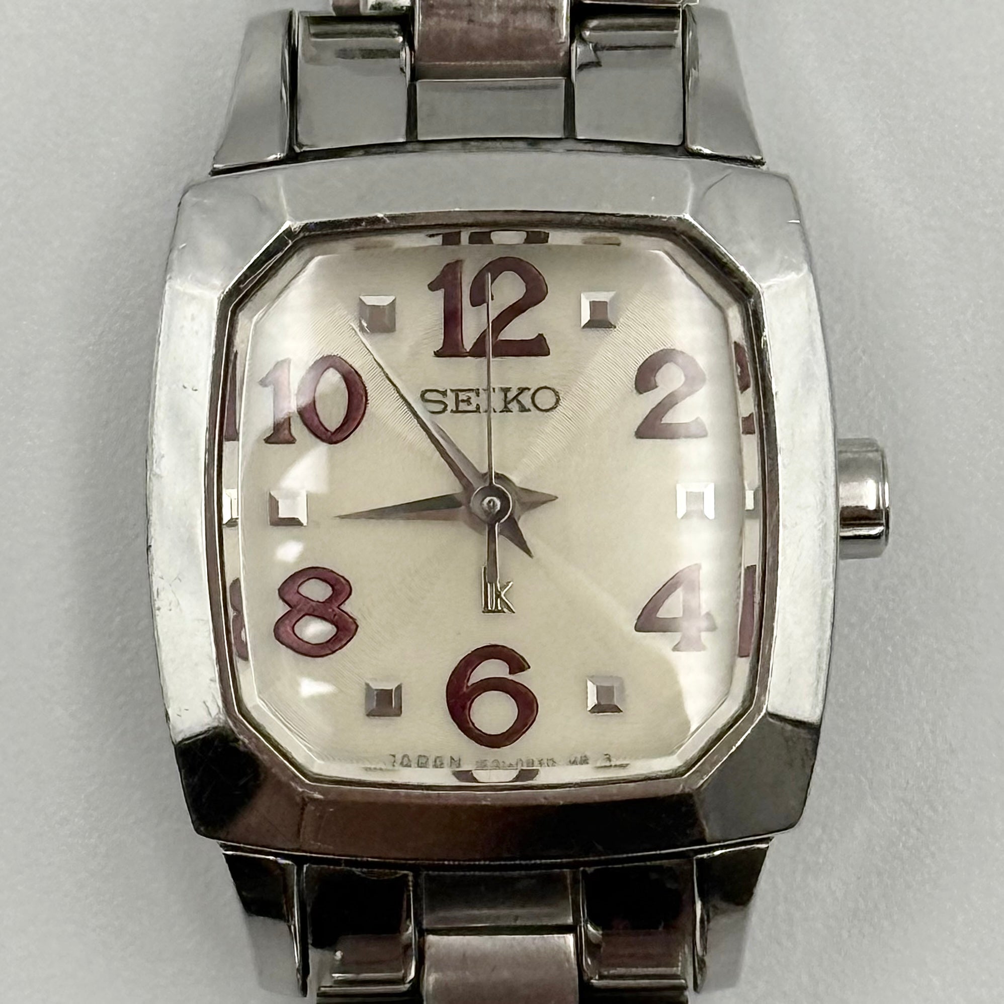 Seiko Lukia stainless steel watch with a rectangular case and silver dial presented on a cushion.