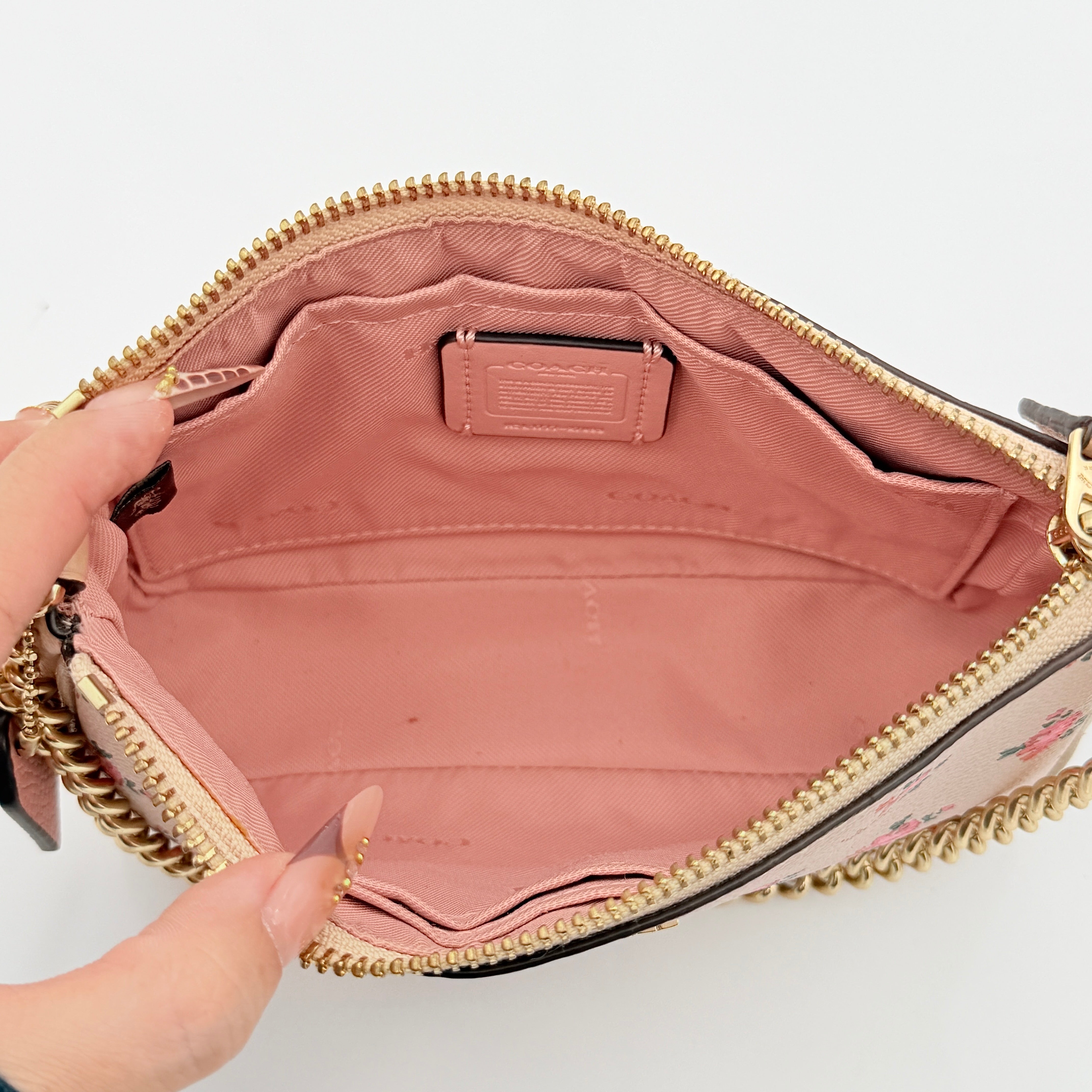 Coach Nolita 19 pink shoulder bag in floral print with gold chain handle, photographed against a white background.