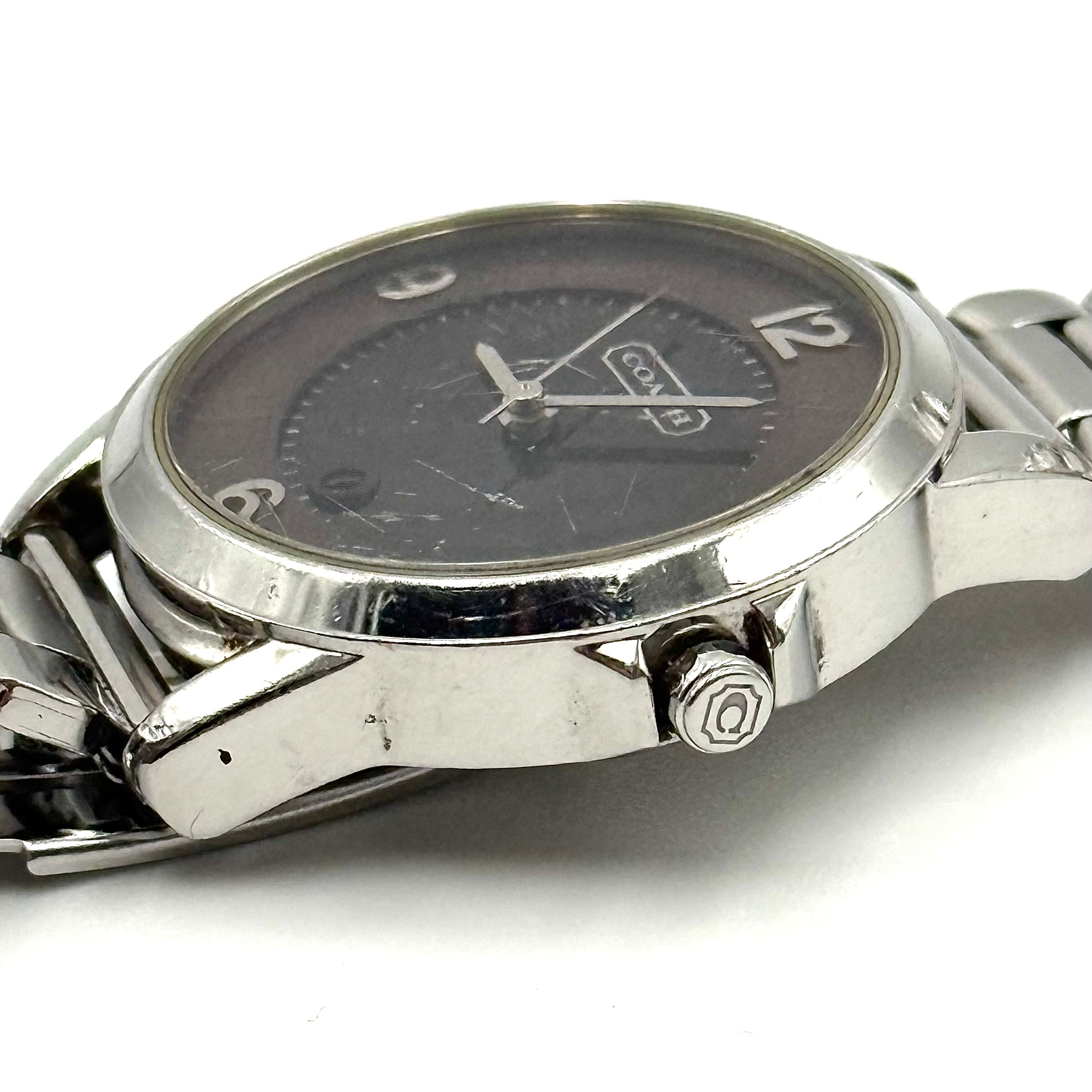 Coach CA.13.7.14.0431 stainless steel watch with brown dial and silver-tone bracelet, presented on a black cushion.