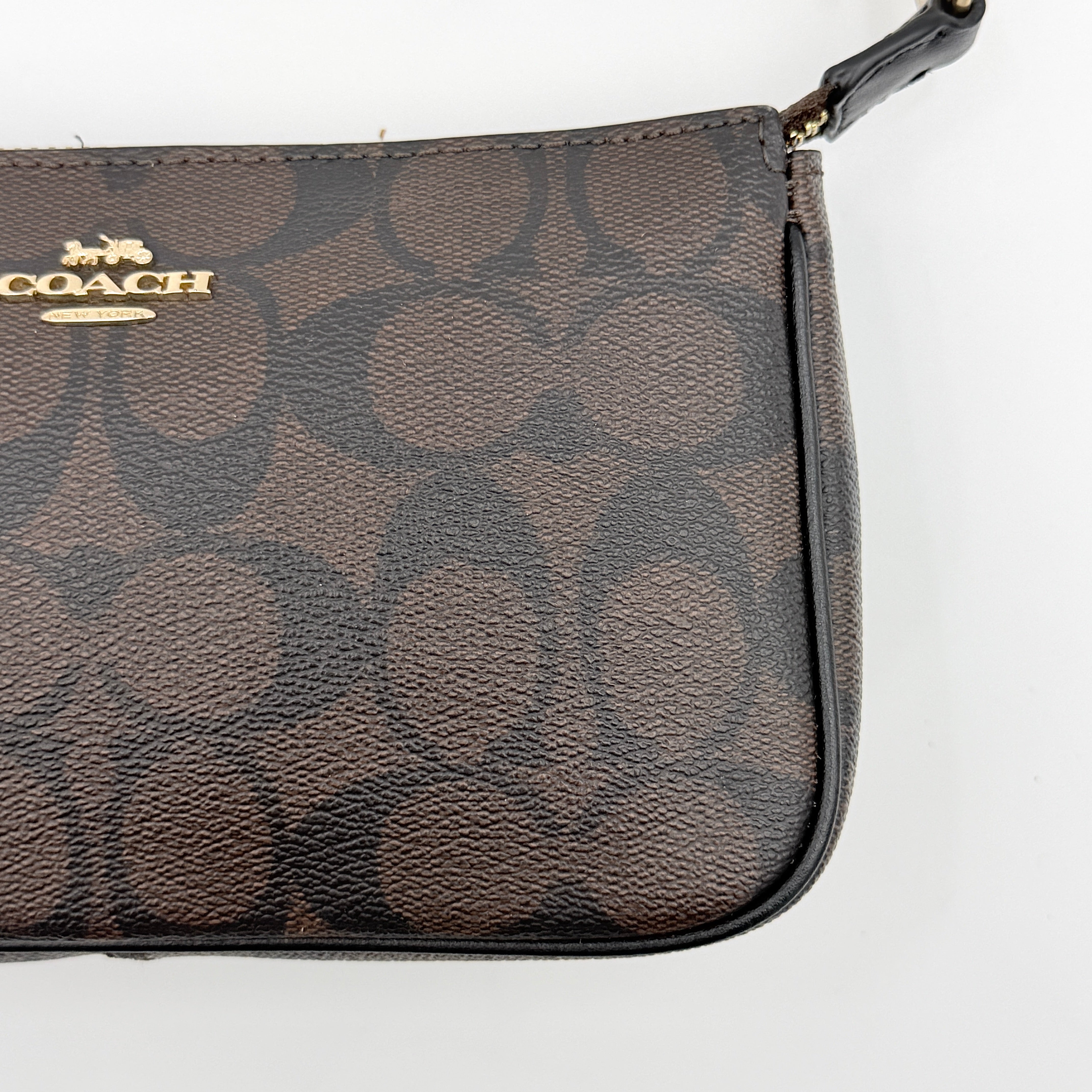 Coach Signature Nolita 19 shoulder bag in brown monogram canvas with black leather strap and gold-tone hardware, shown against a white background.