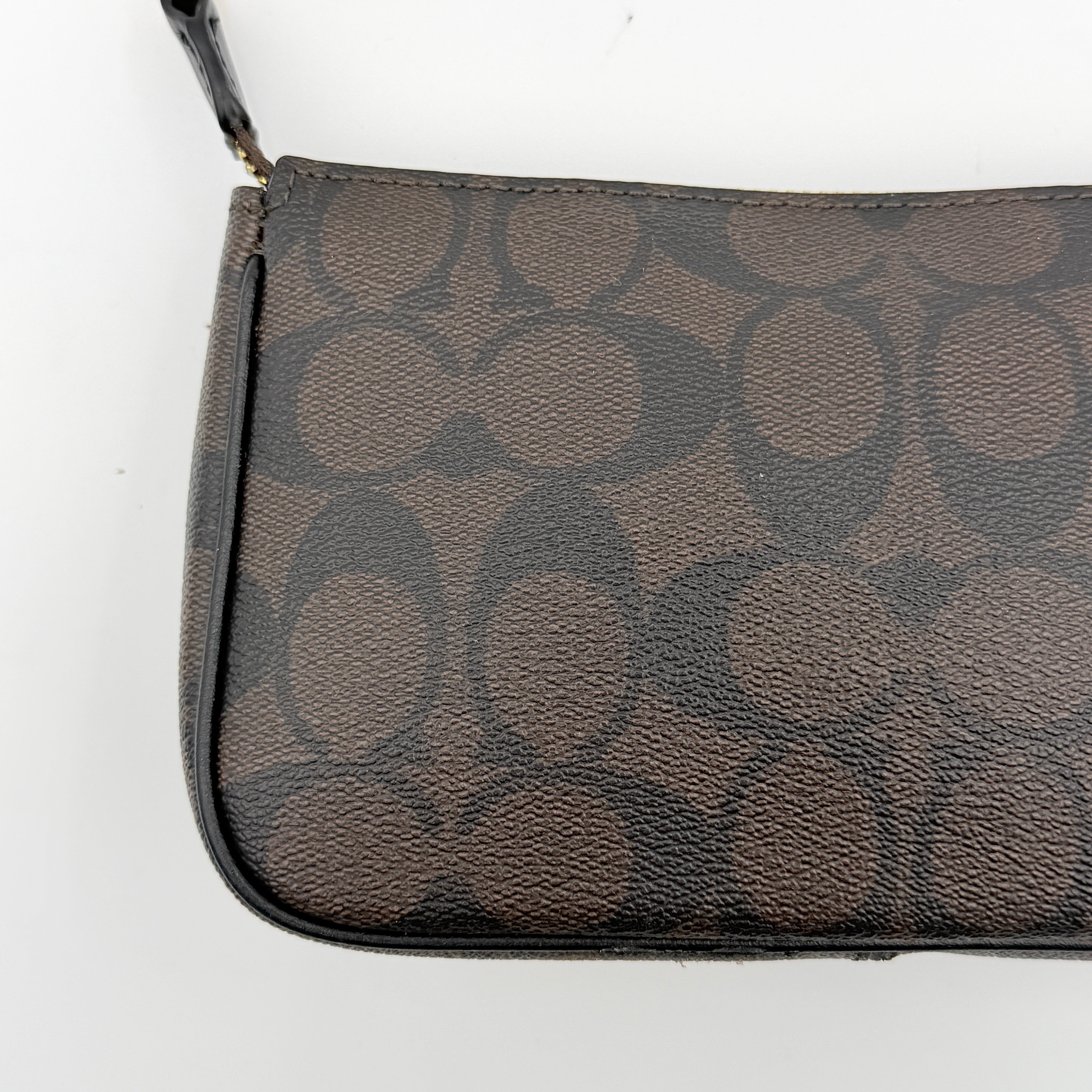 Coach Signature Nolita 19 shoulder bag in brown monogram canvas with black leather strap and gold-tone hardware, shown against a white background.