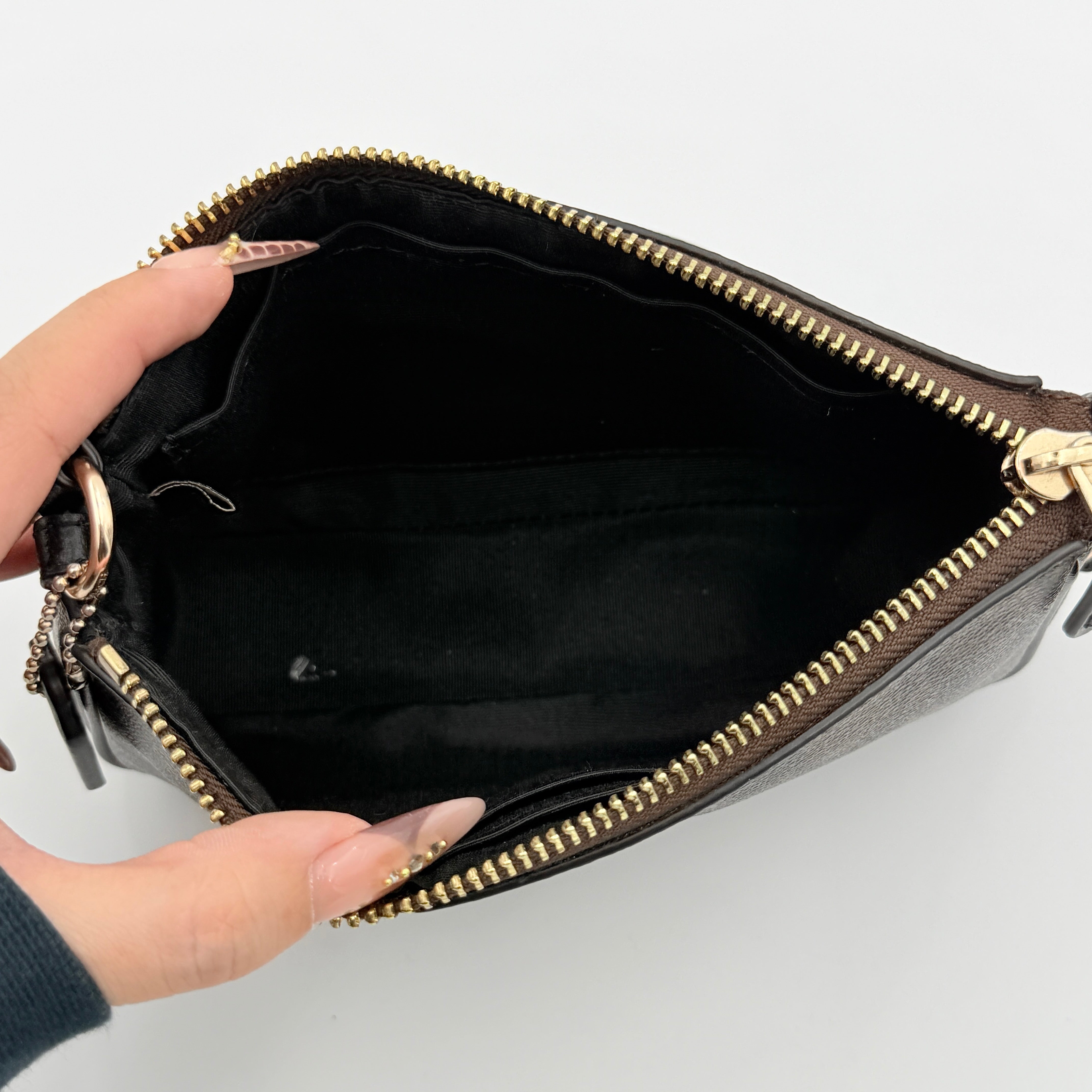 Coach Signature Nolita 19 shoulder bag in brown monogram canvas with black leather strap and gold-tone hardware, shown against a white background.