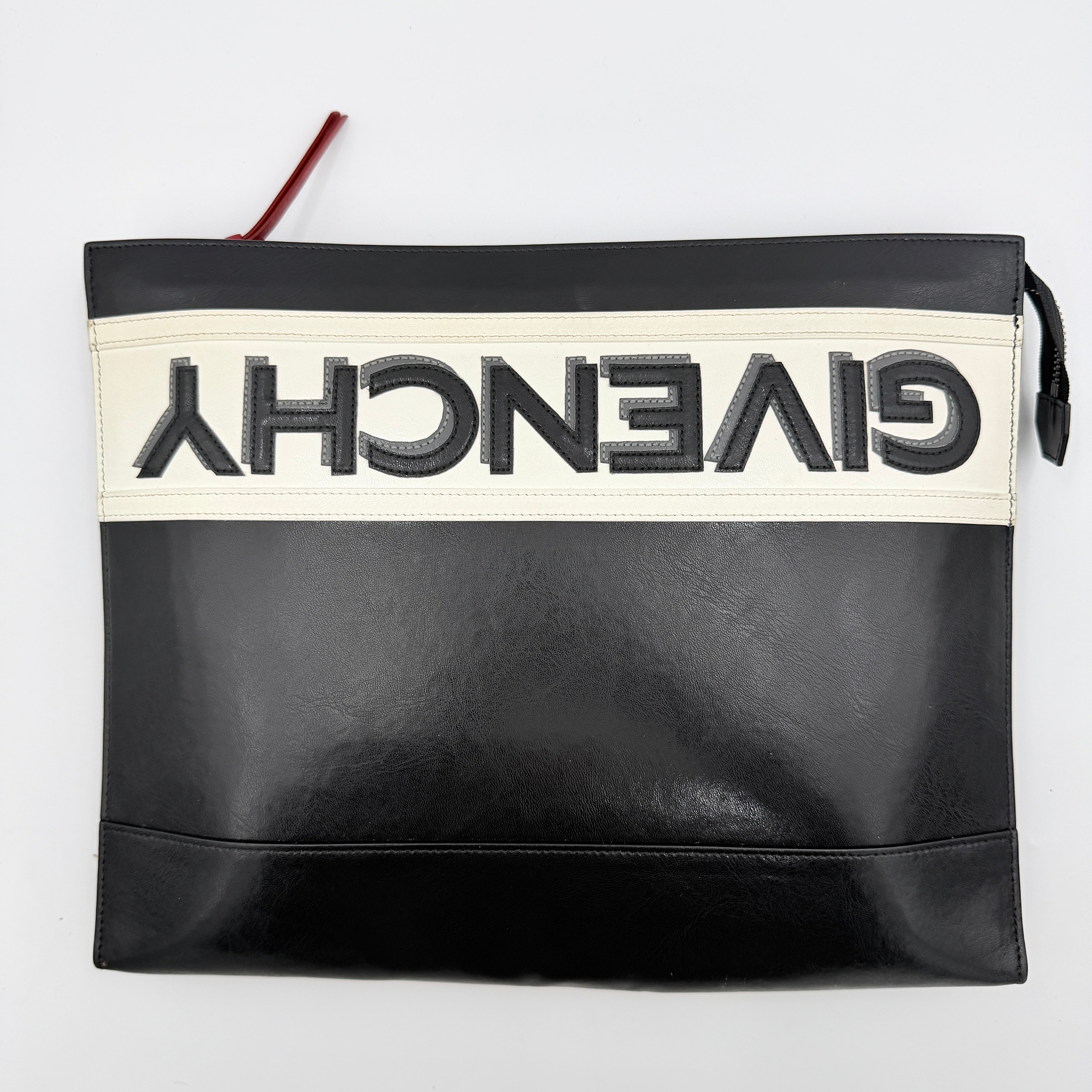 Front view of a Givenchy black leather clutch with bold white logo panel and red zip pull.