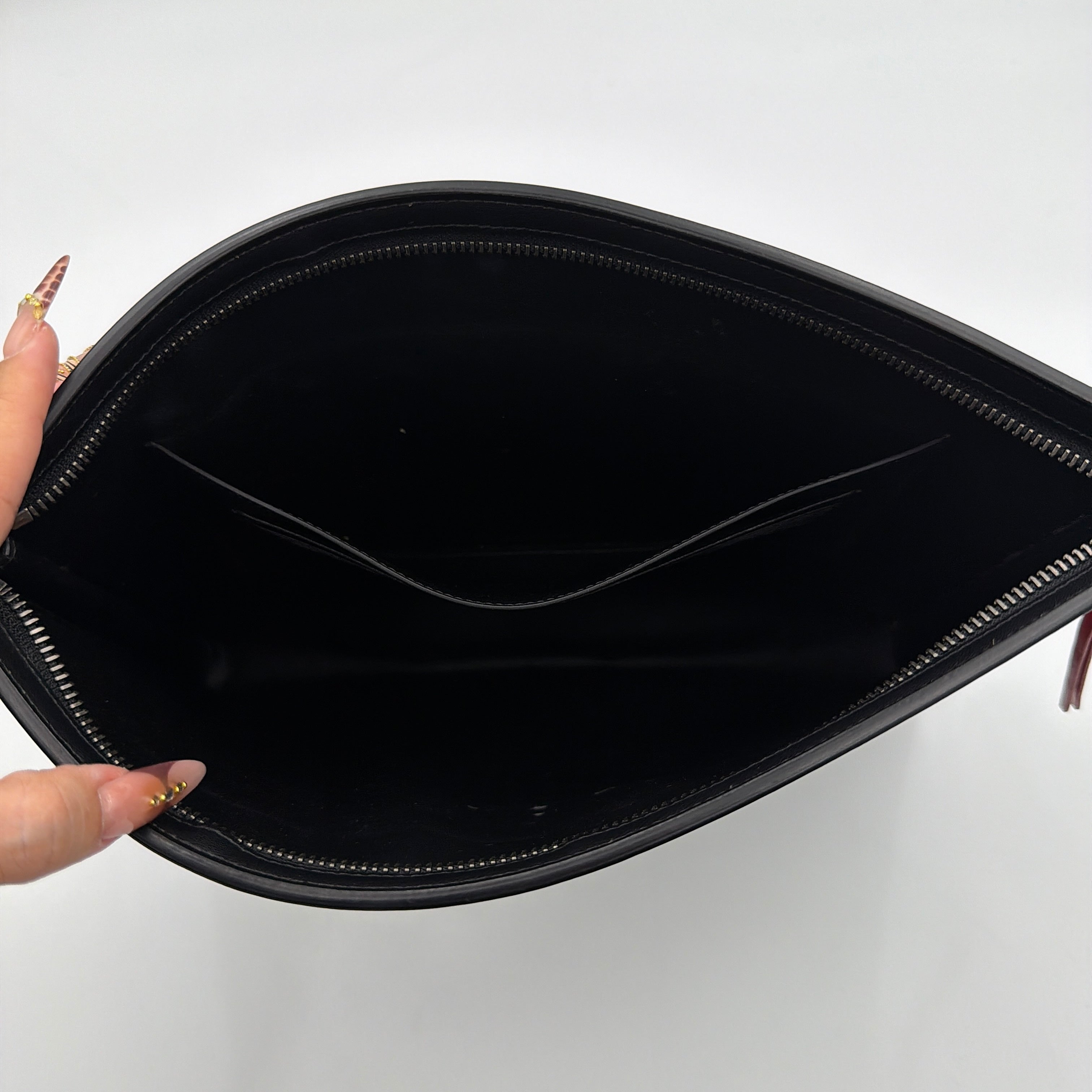Front view of a Givenchy black leather clutch with bold white logo panel and red zip pull.