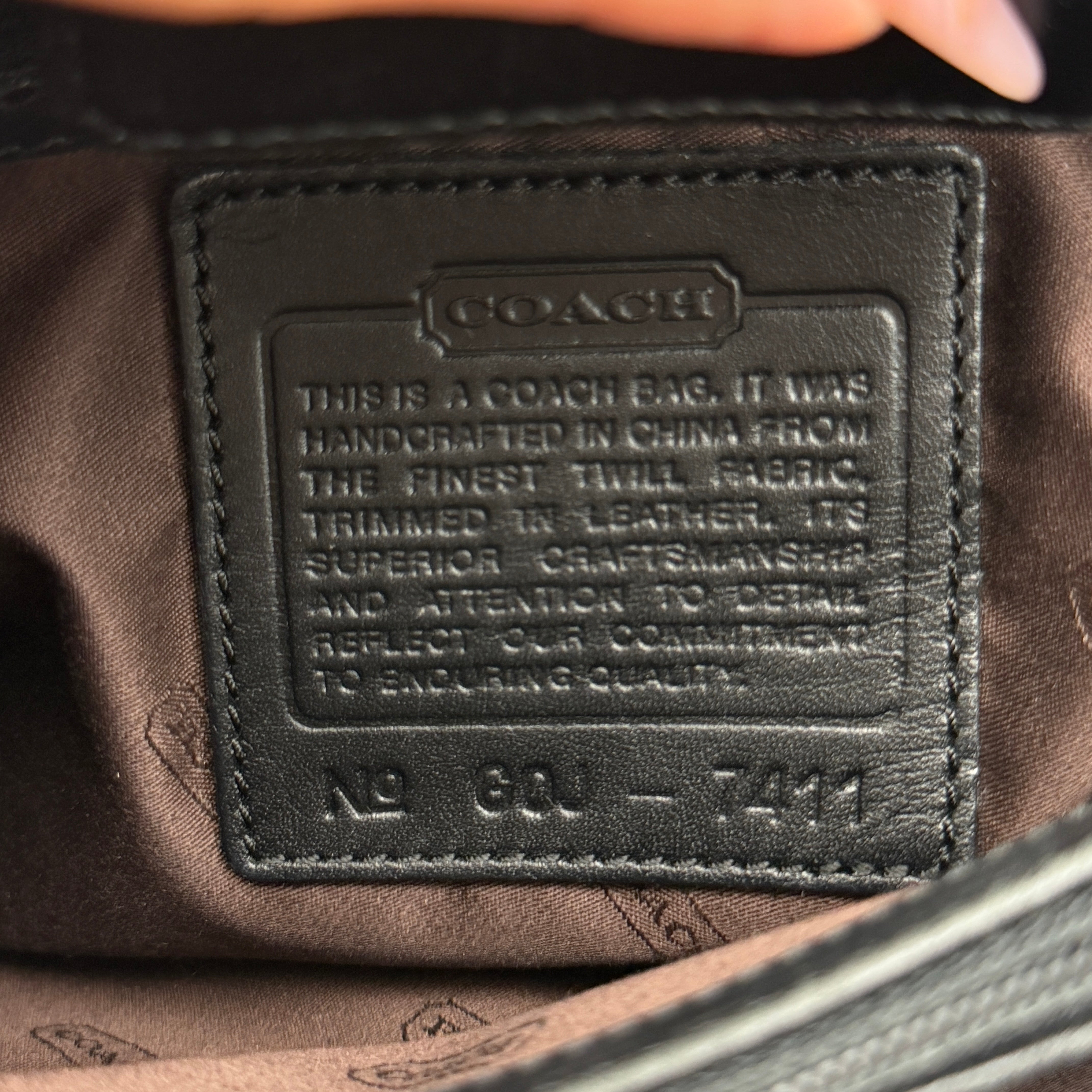 Coach Mercer Nylon Tote Bag in black with leather handles and silver Coach tag, photographed on a white background.
