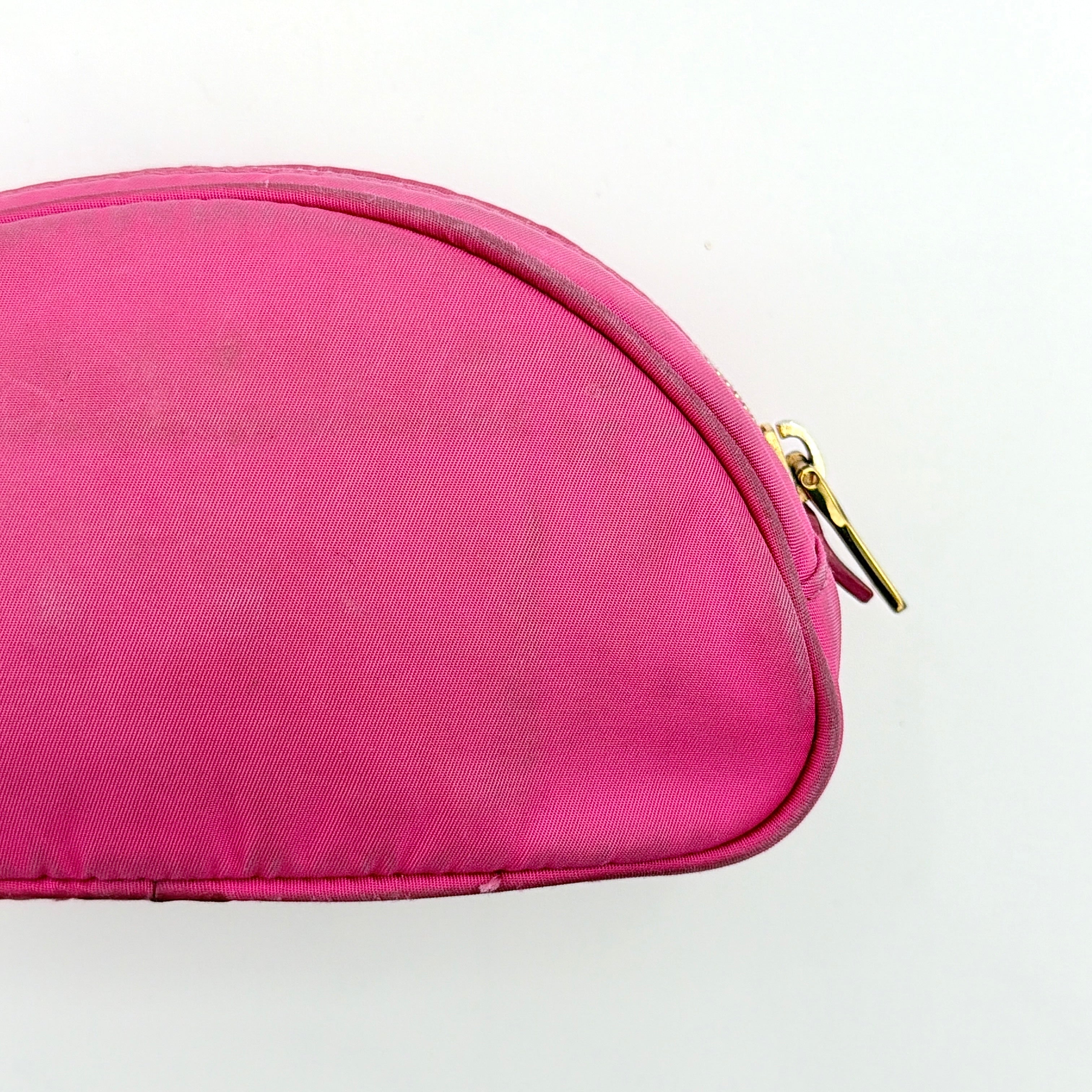 Prada Tessuto Nylon Pouch in vibrant pink with gold-tone hardware and triangle logo, showing visible wear on the exterior.