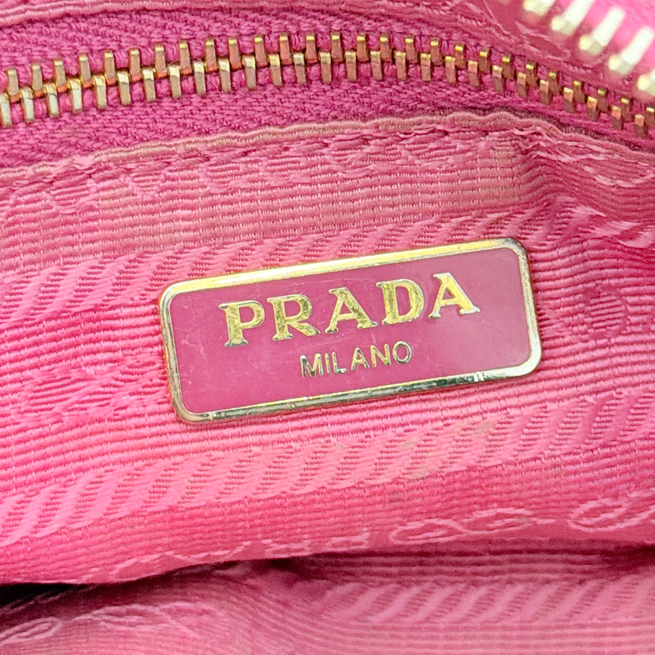 Prada Tessuto Nylon Pouch in vibrant pink with gold-tone hardware and triangle logo, showing visible wear on the exterior.