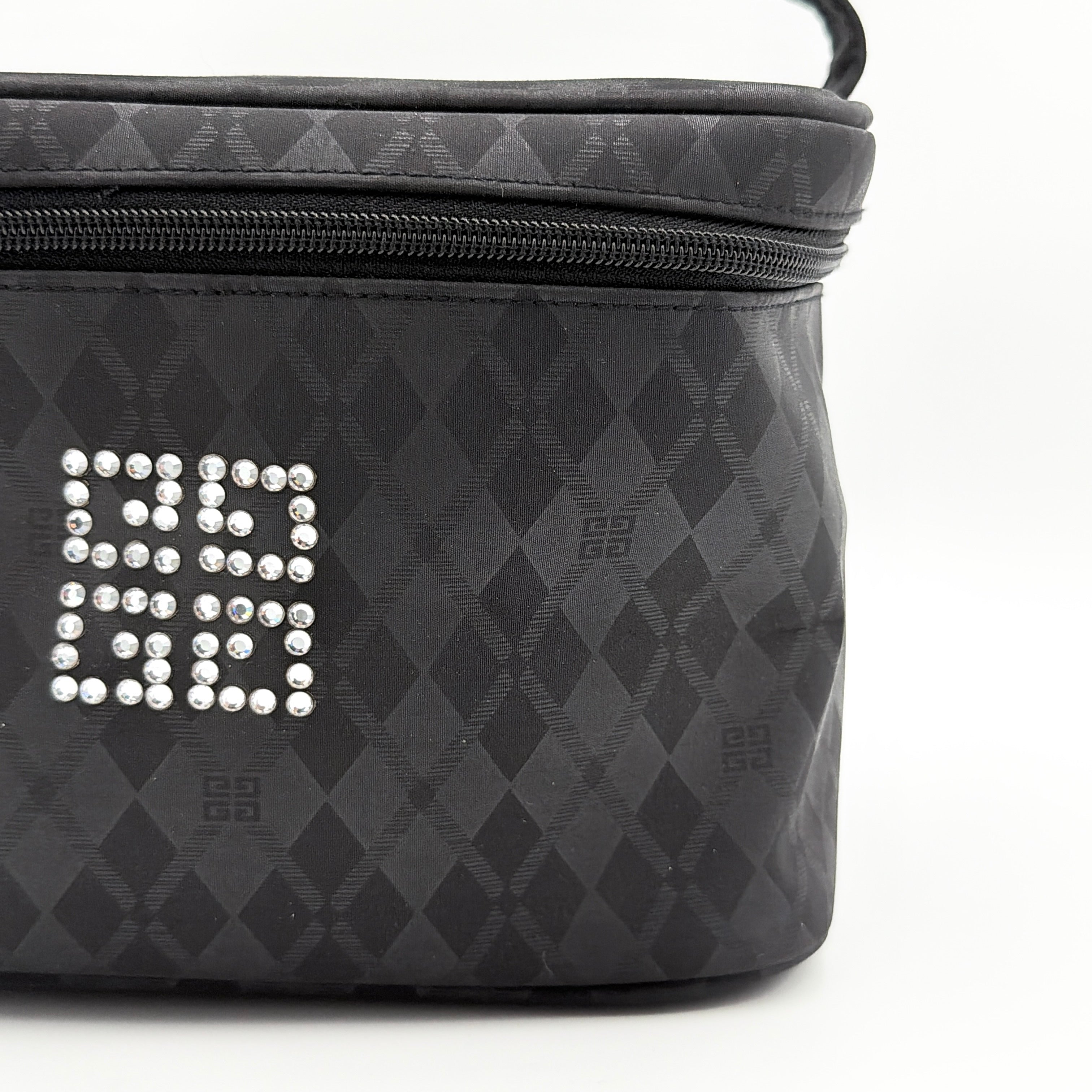 Givenchy vanity bag in black with rhinestone logo, geometric pattern, and top handle, shown from the front.