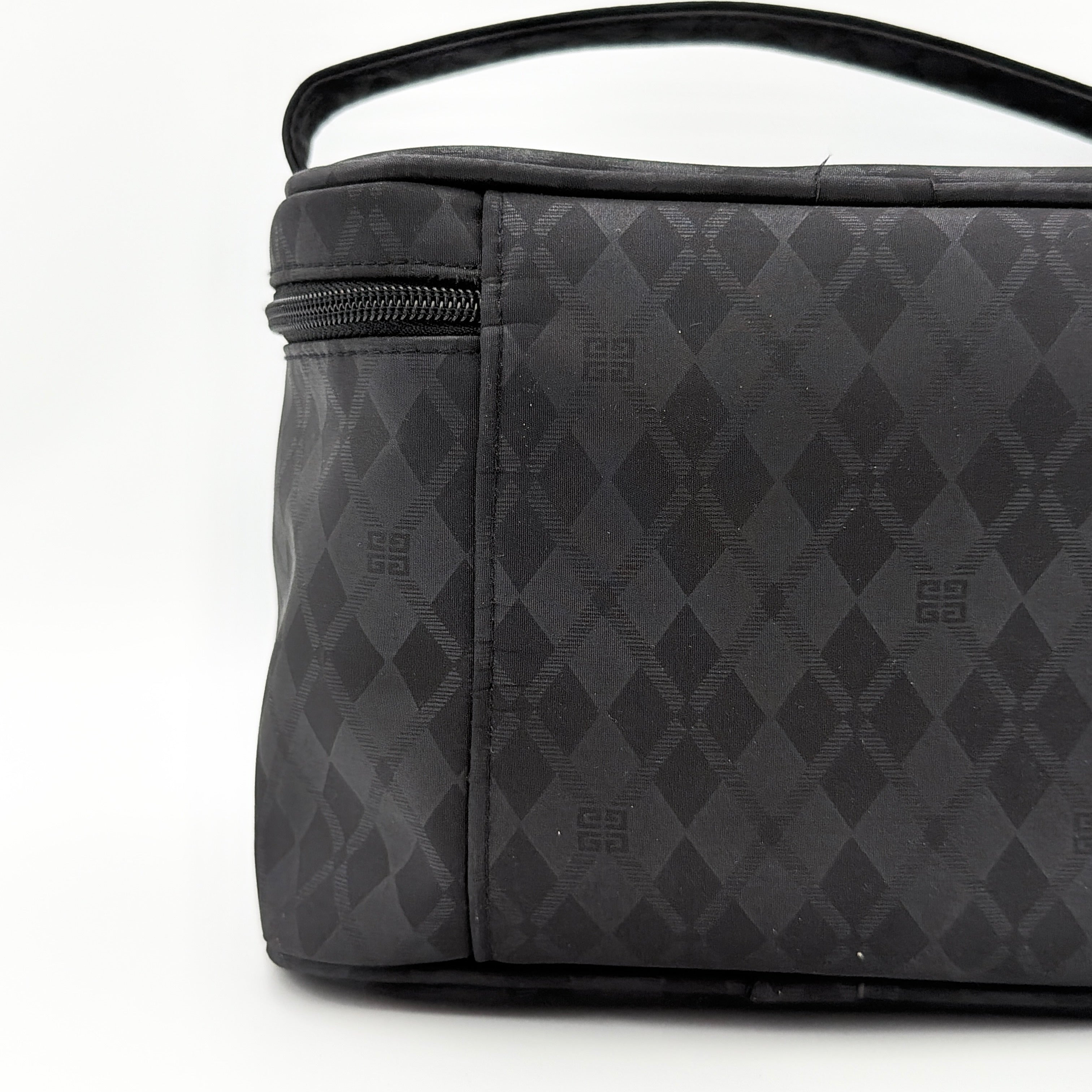 Givenchy vanity bag in black with rhinestone logo, geometric pattern, and top handle, shown from the front.