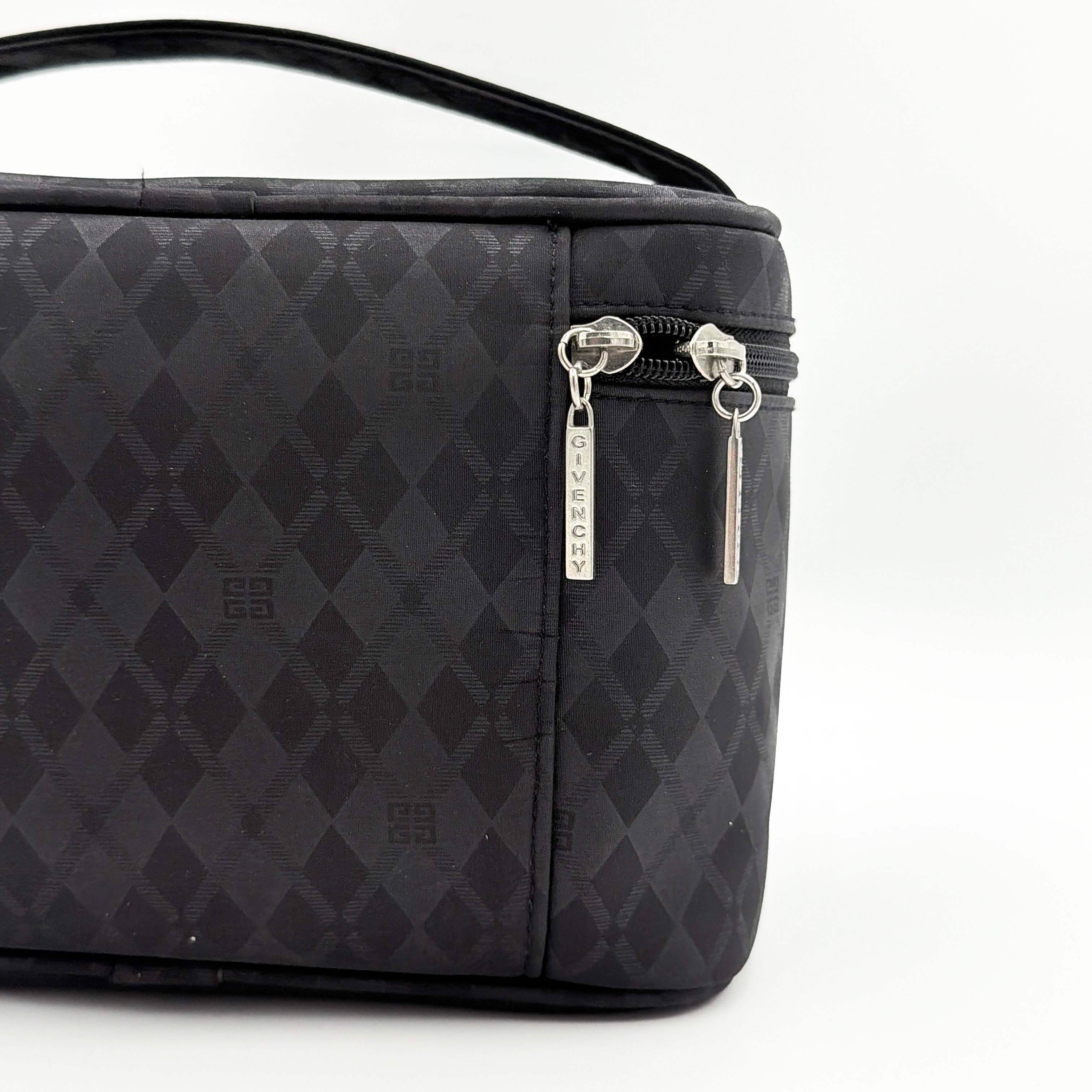 Givenchy vanity bag in black with rhinestone logo, geometric pattern, and top handle, shown from the front.