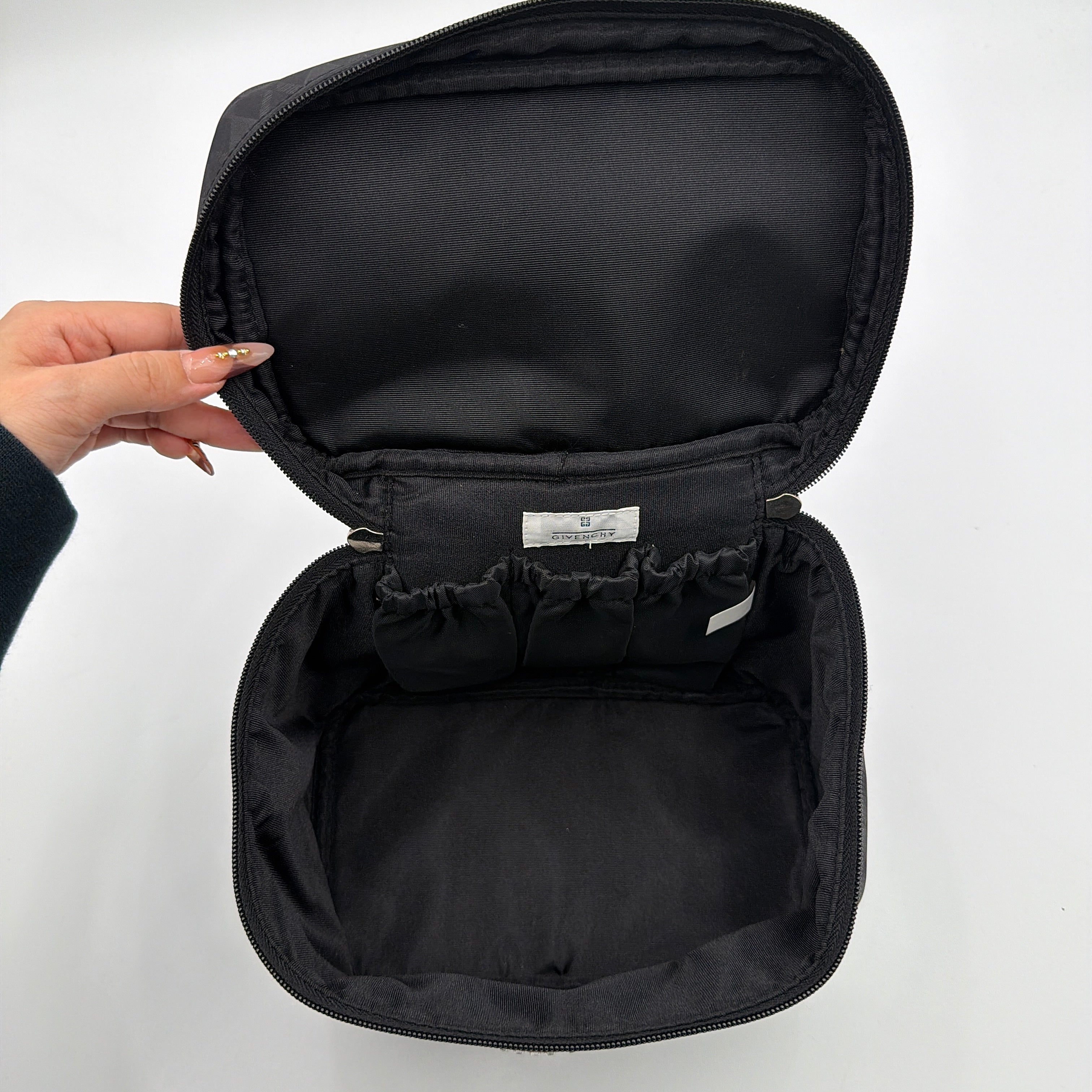 Givenchy vanity bag in black with rhinestone logo, geometric pattern, and top handle, shown from the front.