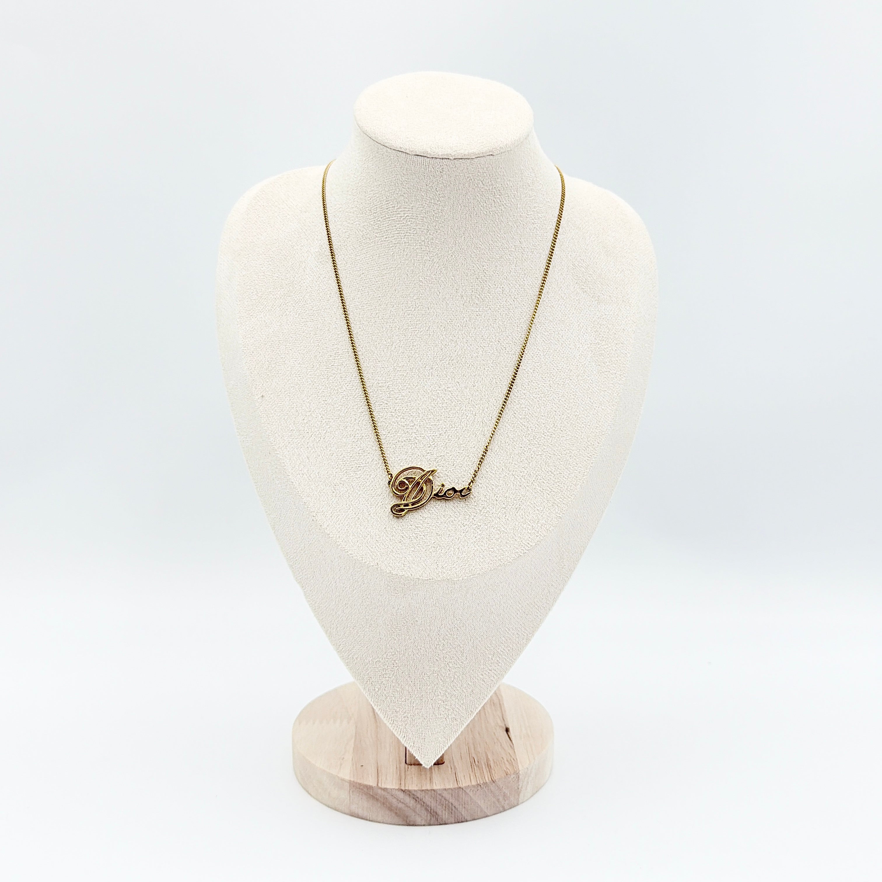 Dior gold logo letter necklace featuring an elegant script pendant on a fine gold chain.