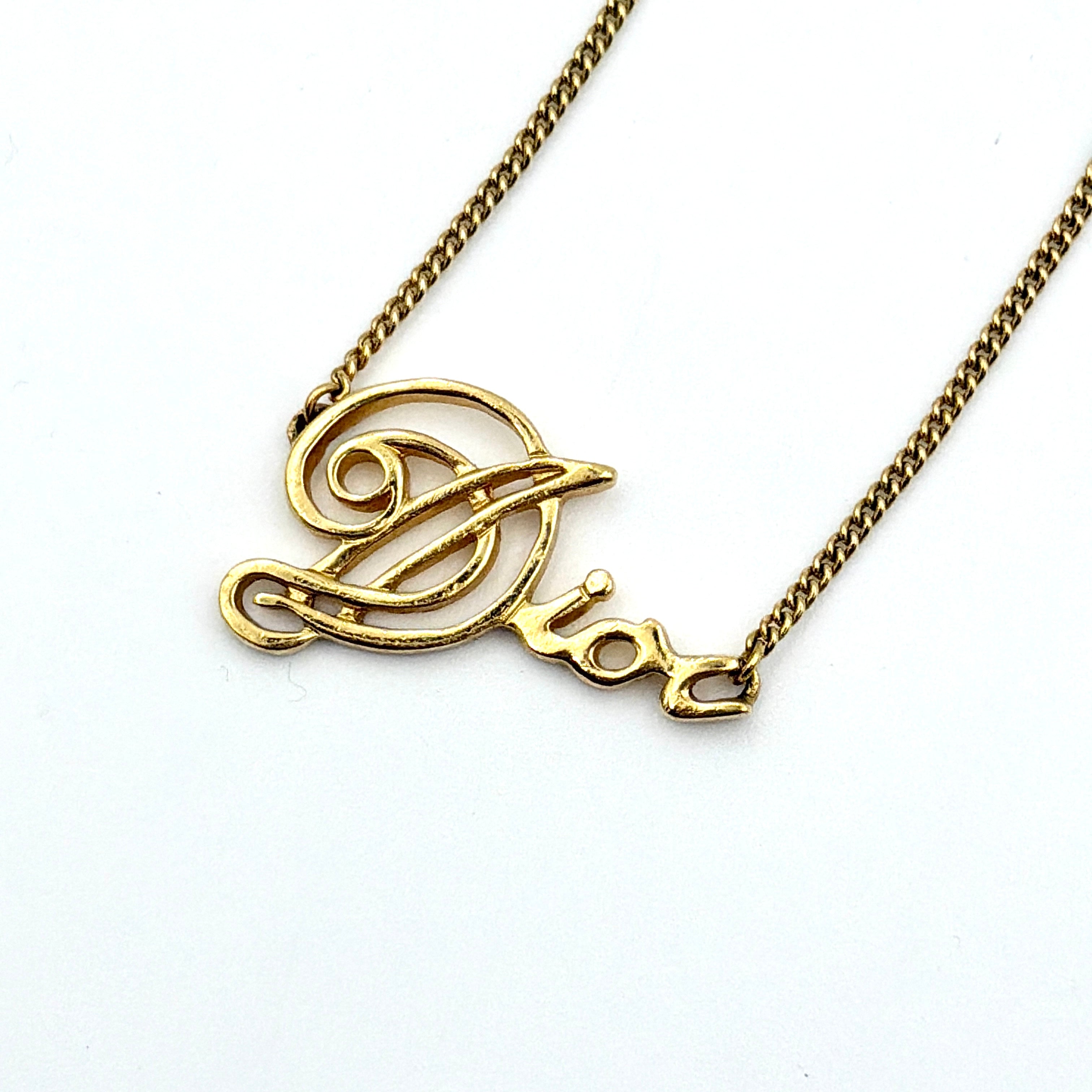 Dior gold logo letter necklace featuring an elegant script pendant on a fine gold chain.