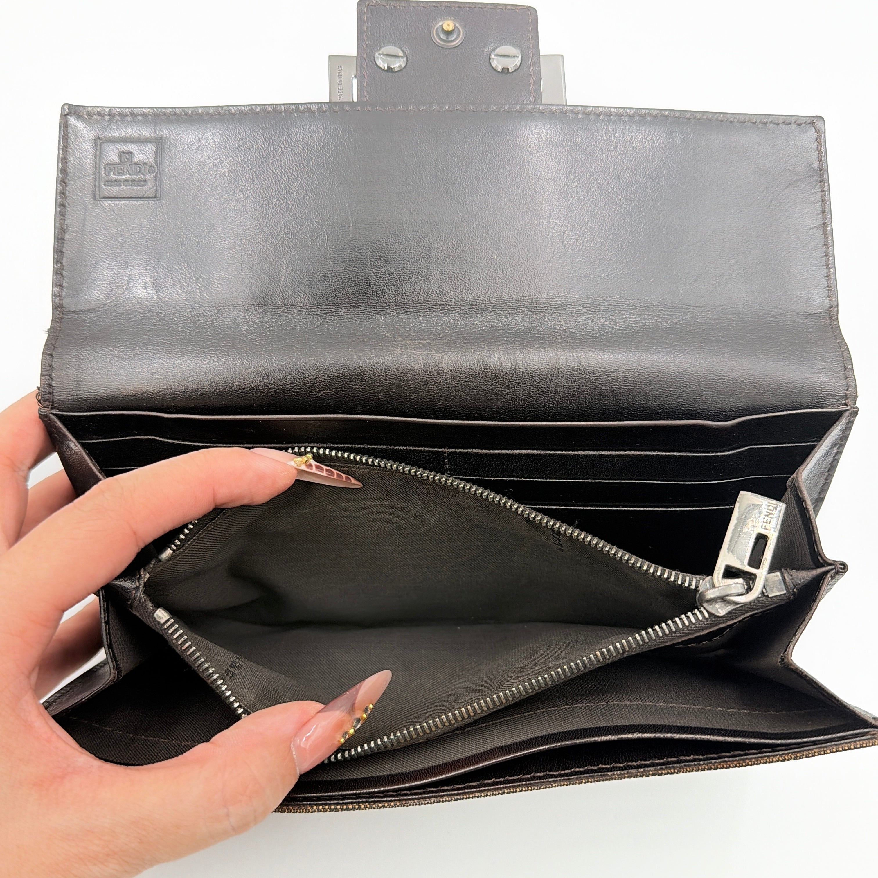 Front view of the Fendi FF Zucca long wallet in brown with signature monogram canvas and silver logo buckle.