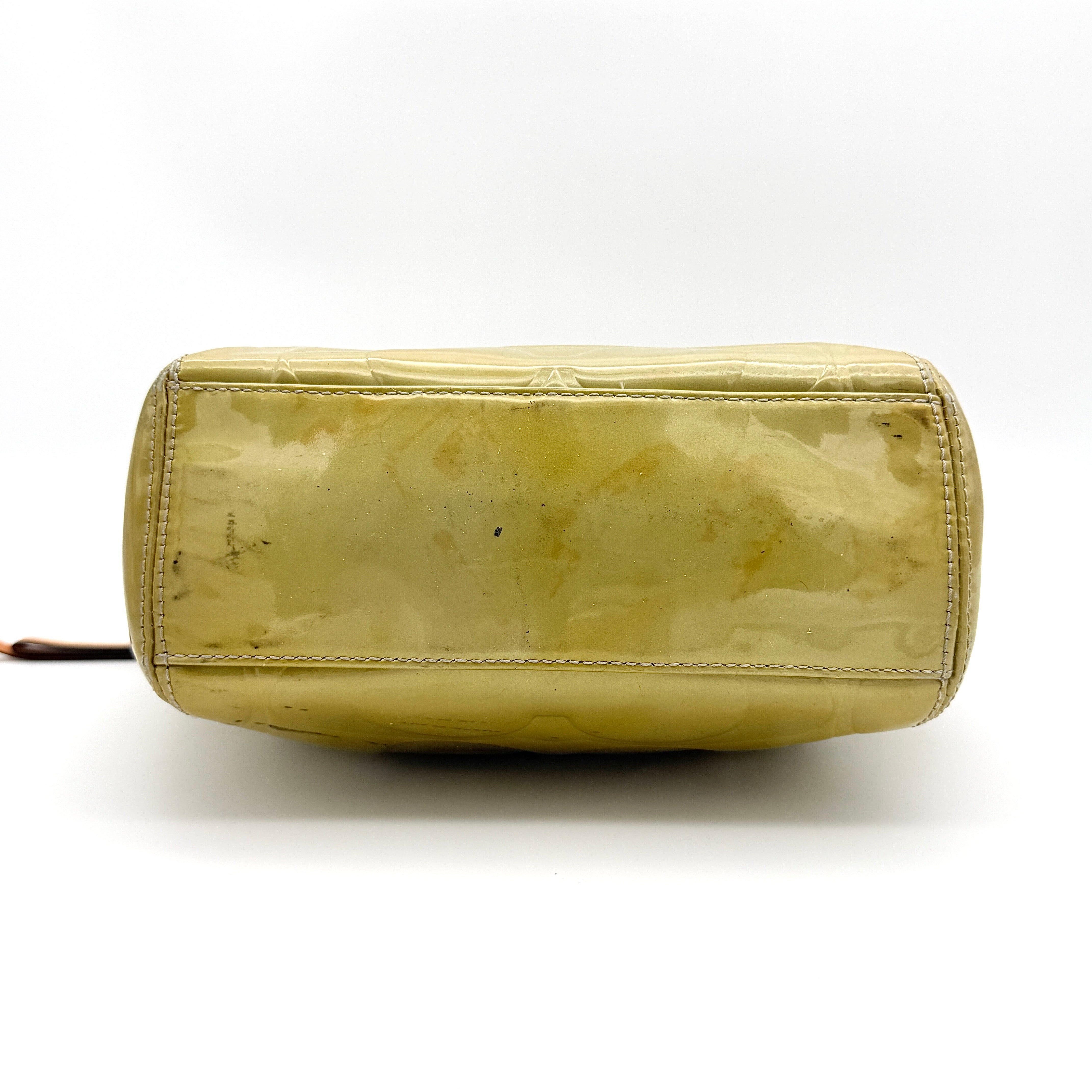 Coach Peyton embossed patent shoulder bag in yellow with tan leather trim and double handles, shown against a white background.