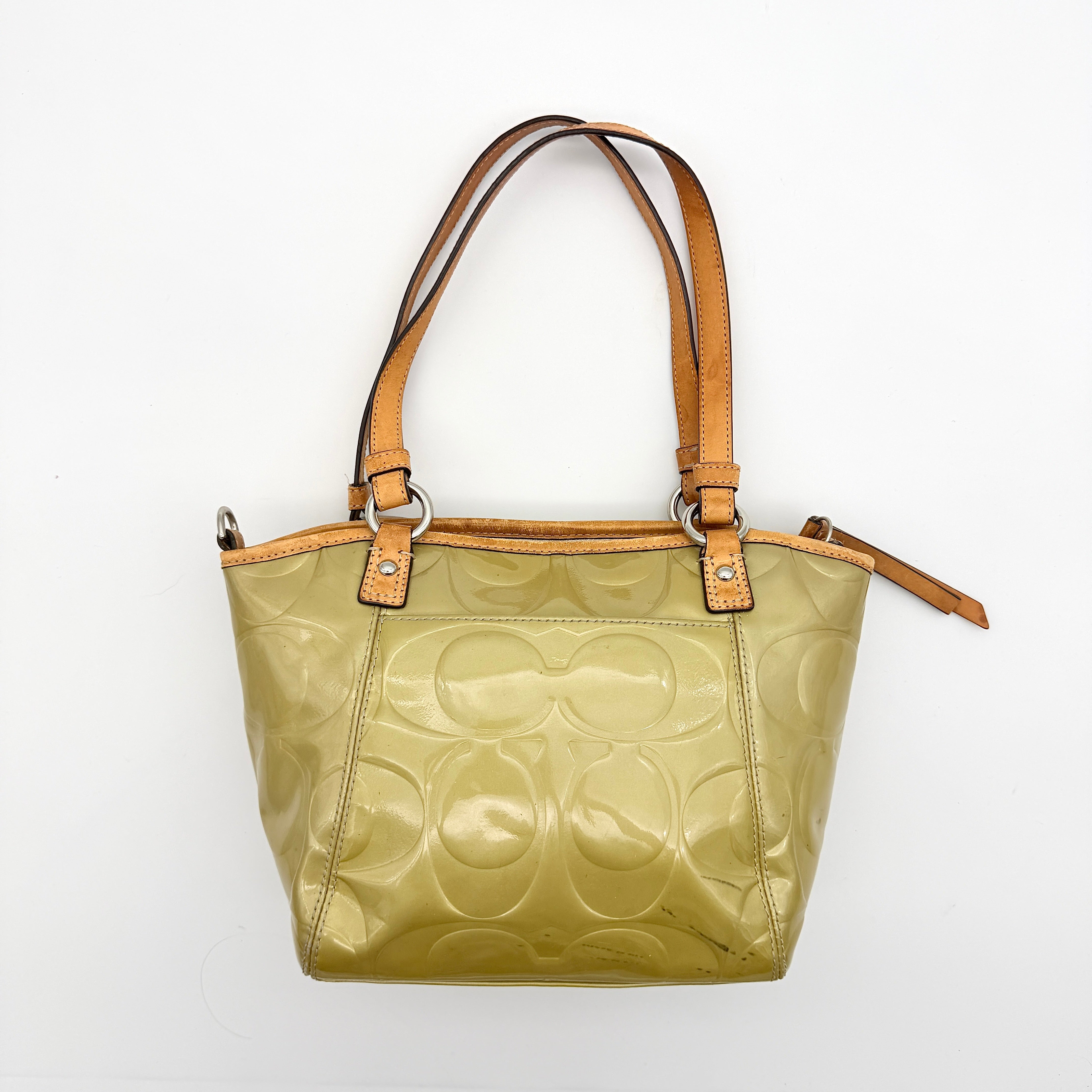 Coach Peyton embossed patent shoulder bag in yellow with tan leather trim and double handles, shown against a white background.