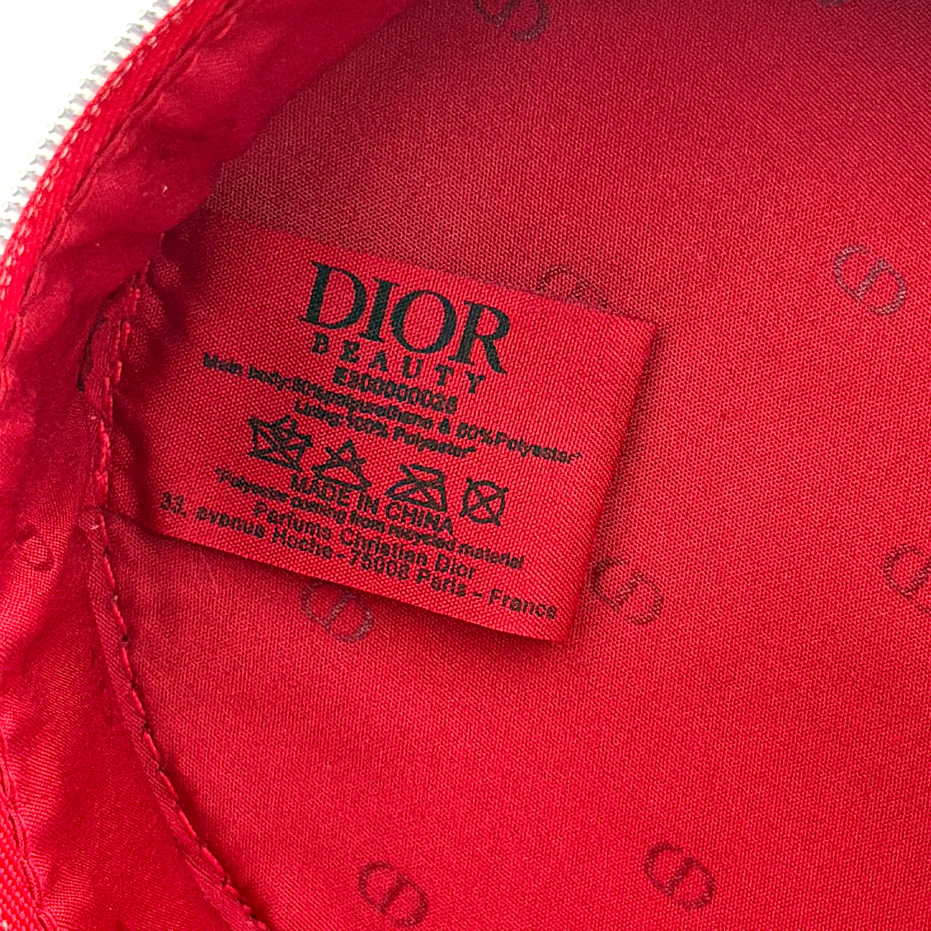 Christian Dior patent leather cosmetic pouch in glossy red with embossed DIOR logo and gold zip hardware.