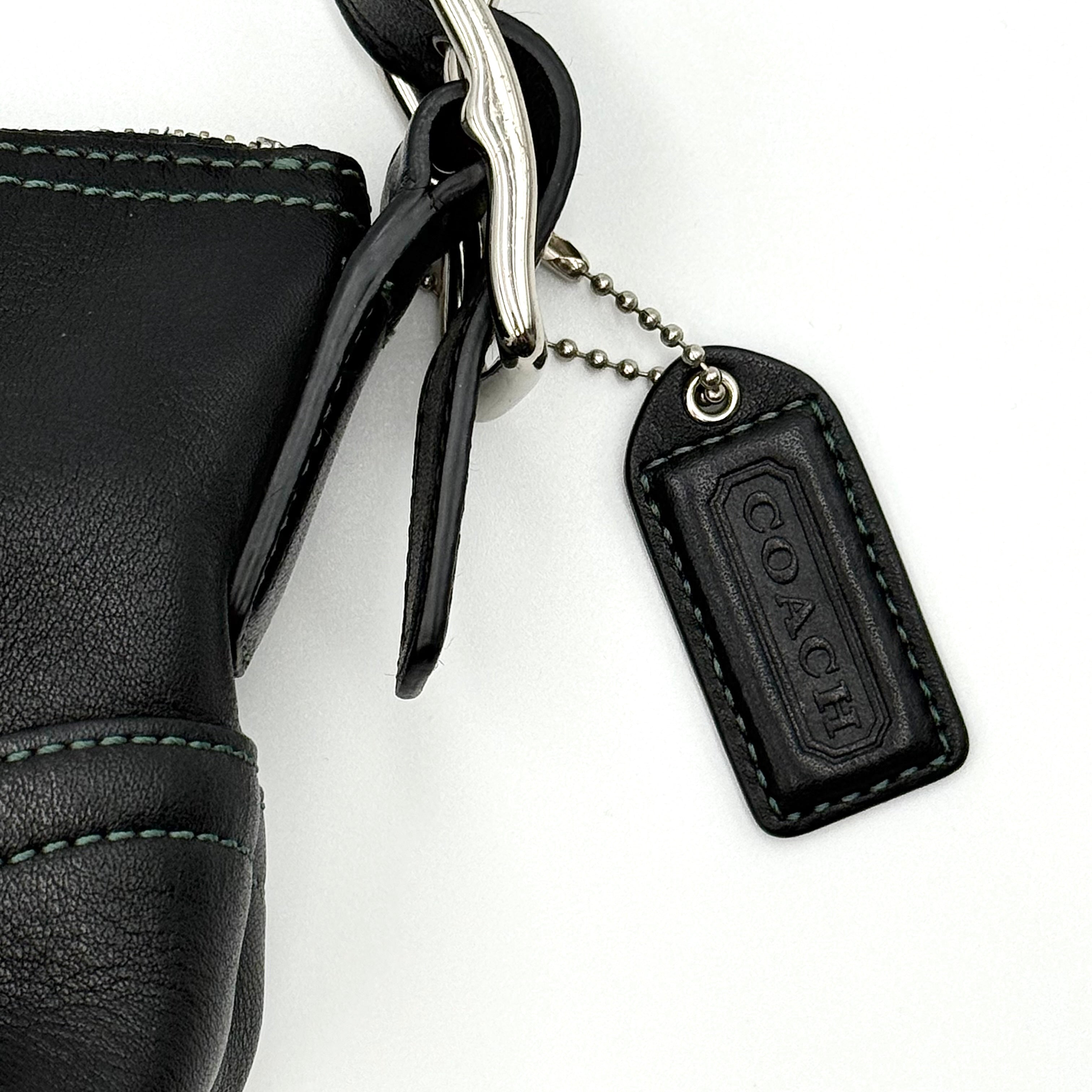 Coach Hampton Demi Baguette shoulder bag in smooth black leather with a curved top handle and silver-tone hardware.