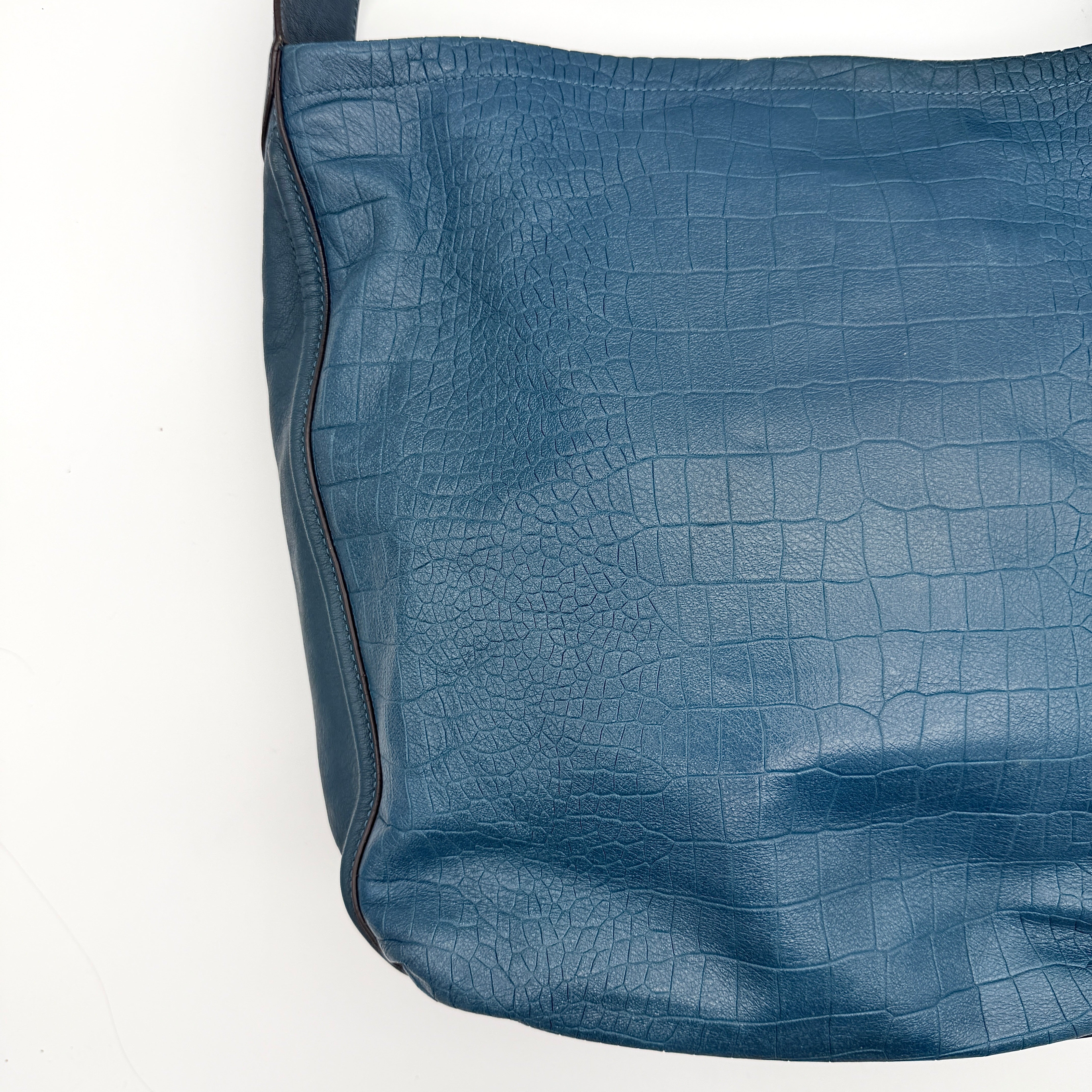 Coach Avery croc-embossed blue leather hobo shoulder bag with single handle and silver hardware against a white background.