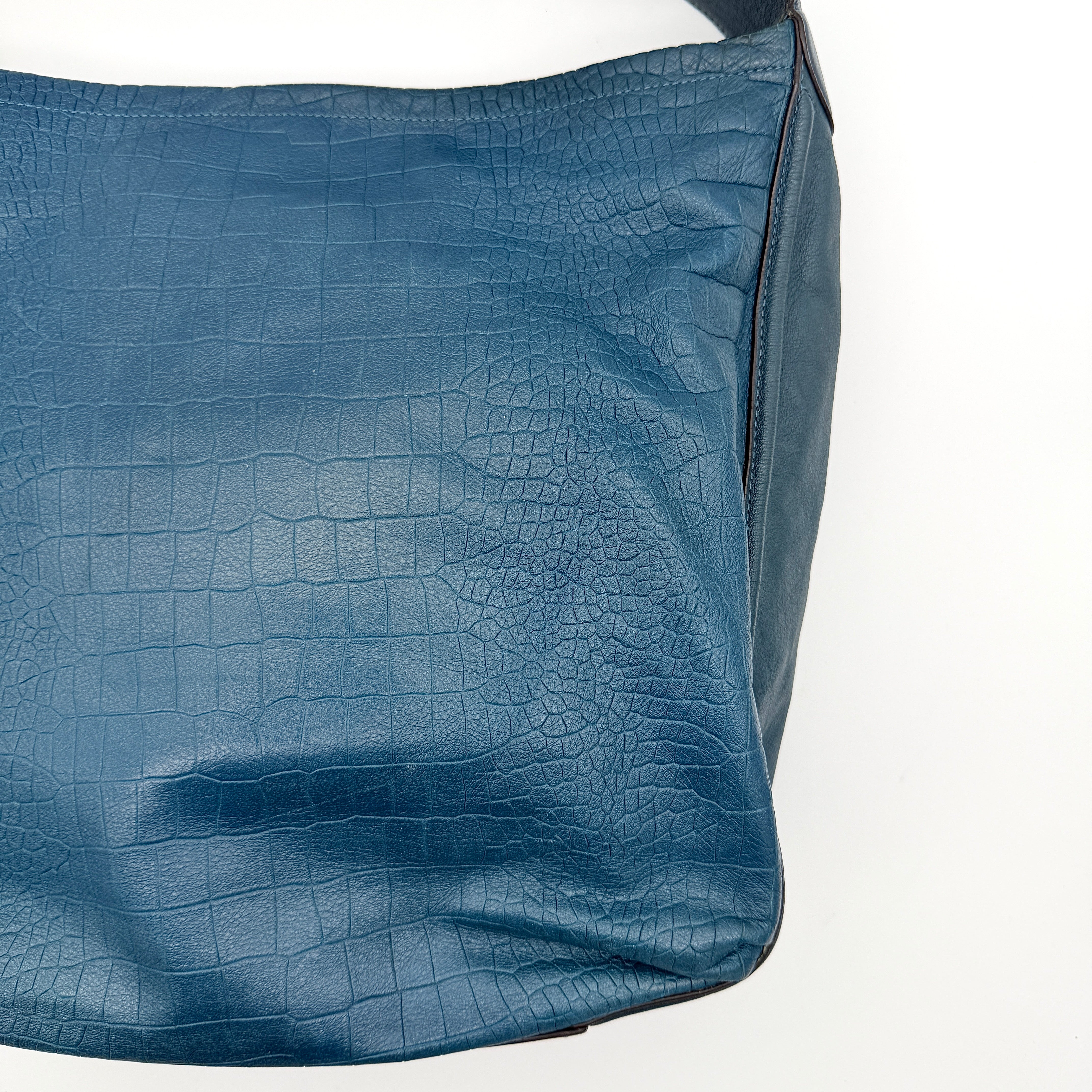 Coach Avery croc-embossed blue leather hobo shoulder bag with single handle and silver hardware against a white background.