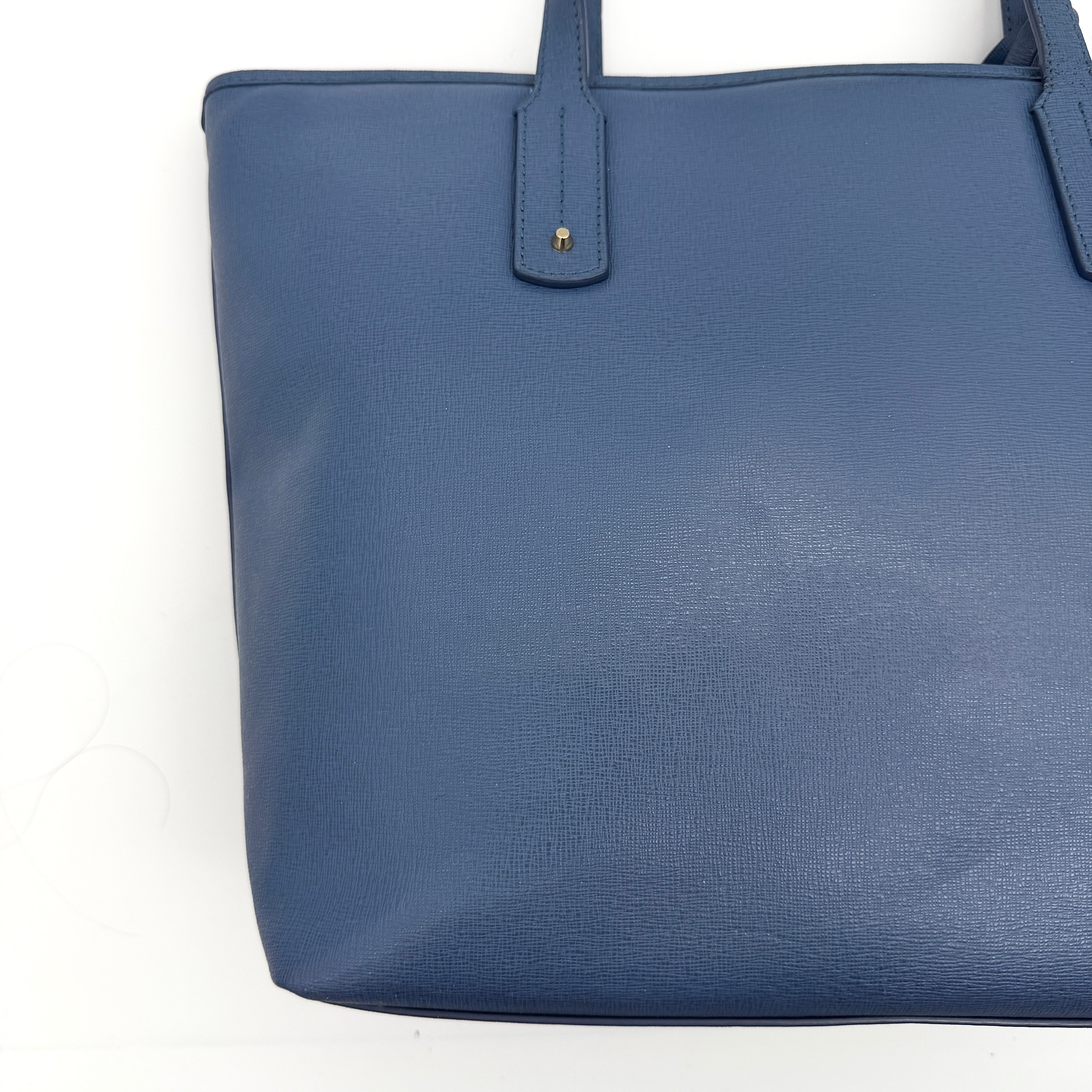 Furla New Daisy Tote Bag in blue leather with gold-tone logo charm and double handles, displayed against a white background