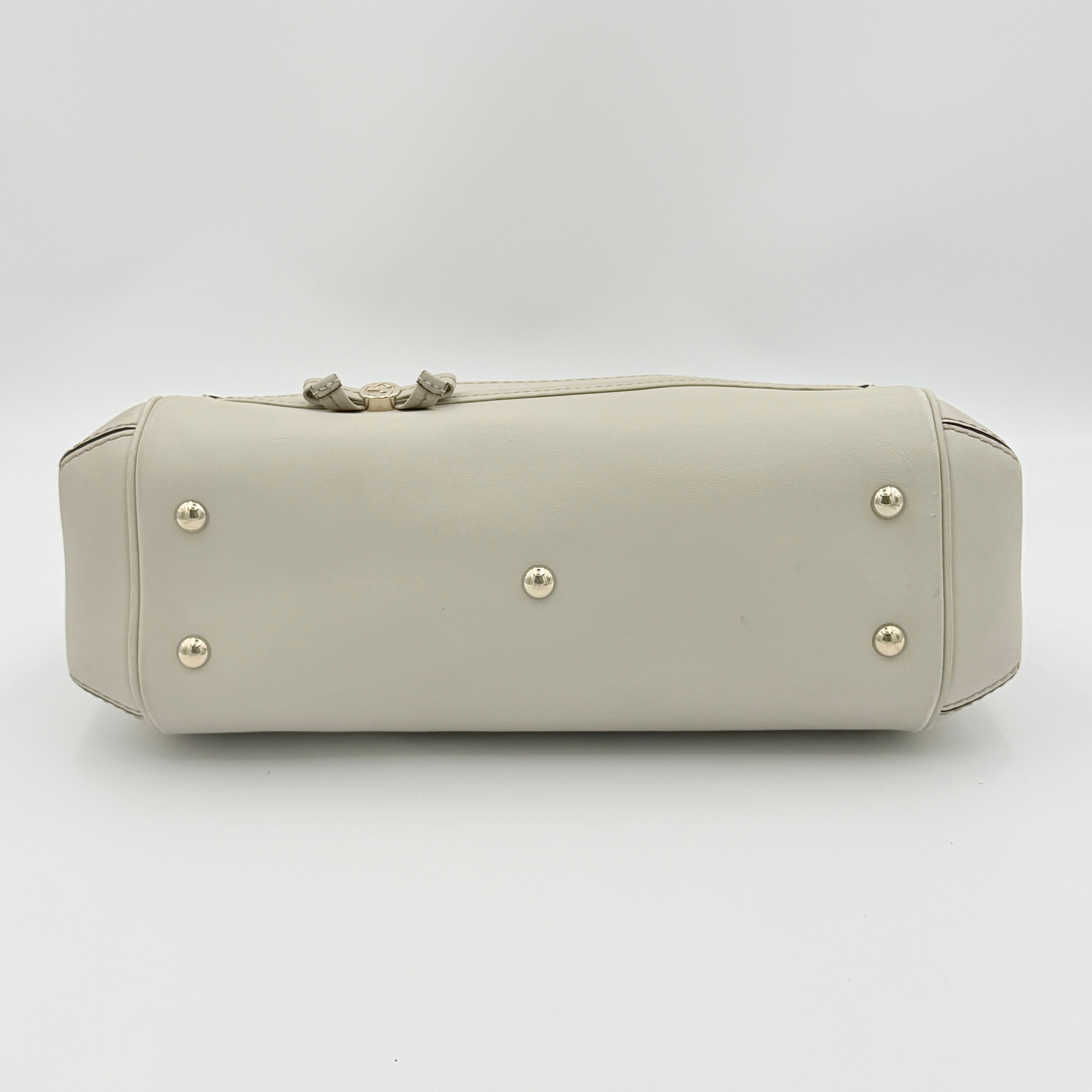 Gucci Mayfair Bow 2Way shoulder bag in cream GG monogram leather with dual handles and detachable strap, styled against a neutral backdrop.