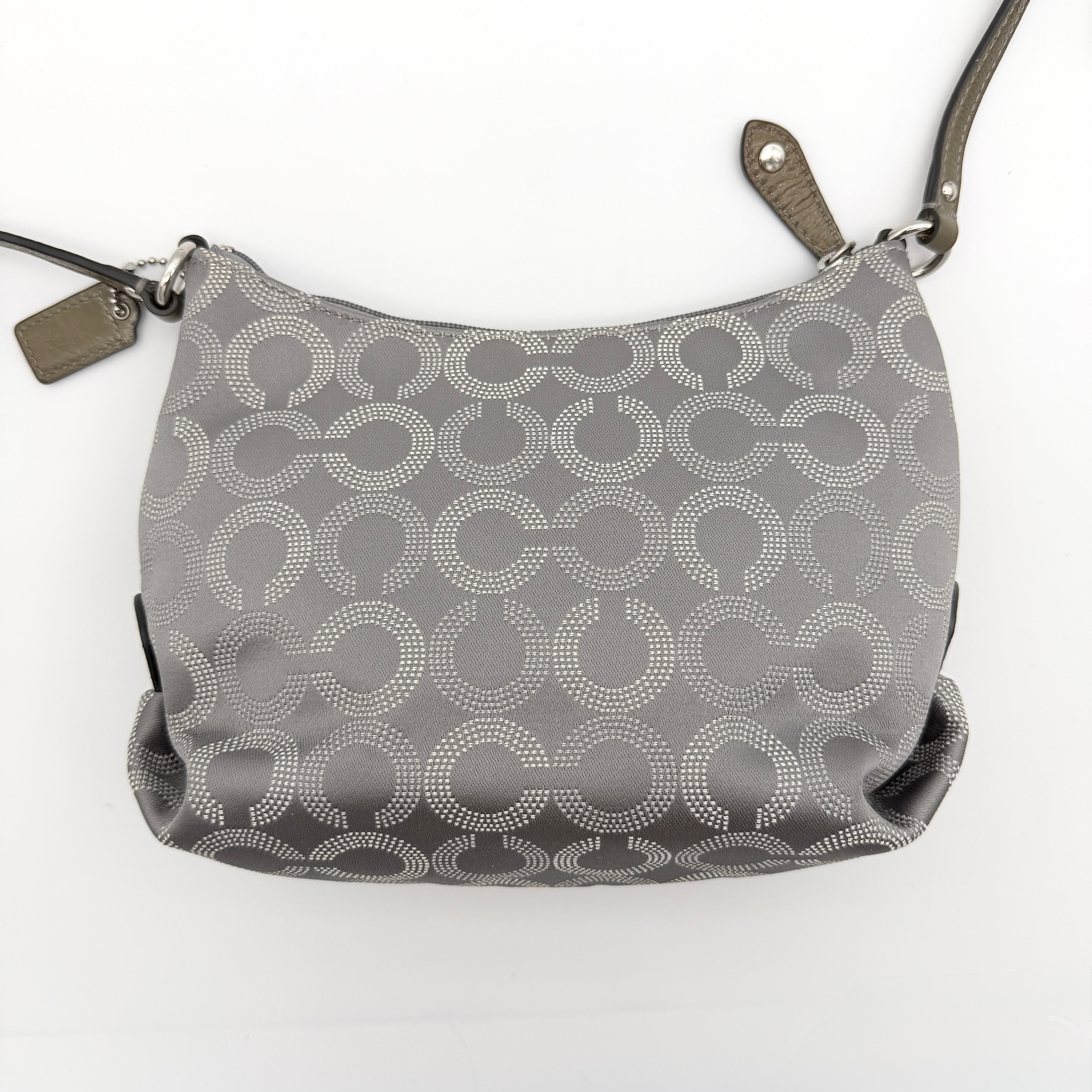 Coach Ashley Dotted Op Art crossbody bag in grey canvas with dotted monogram and adjustable strap, shown against a white background.