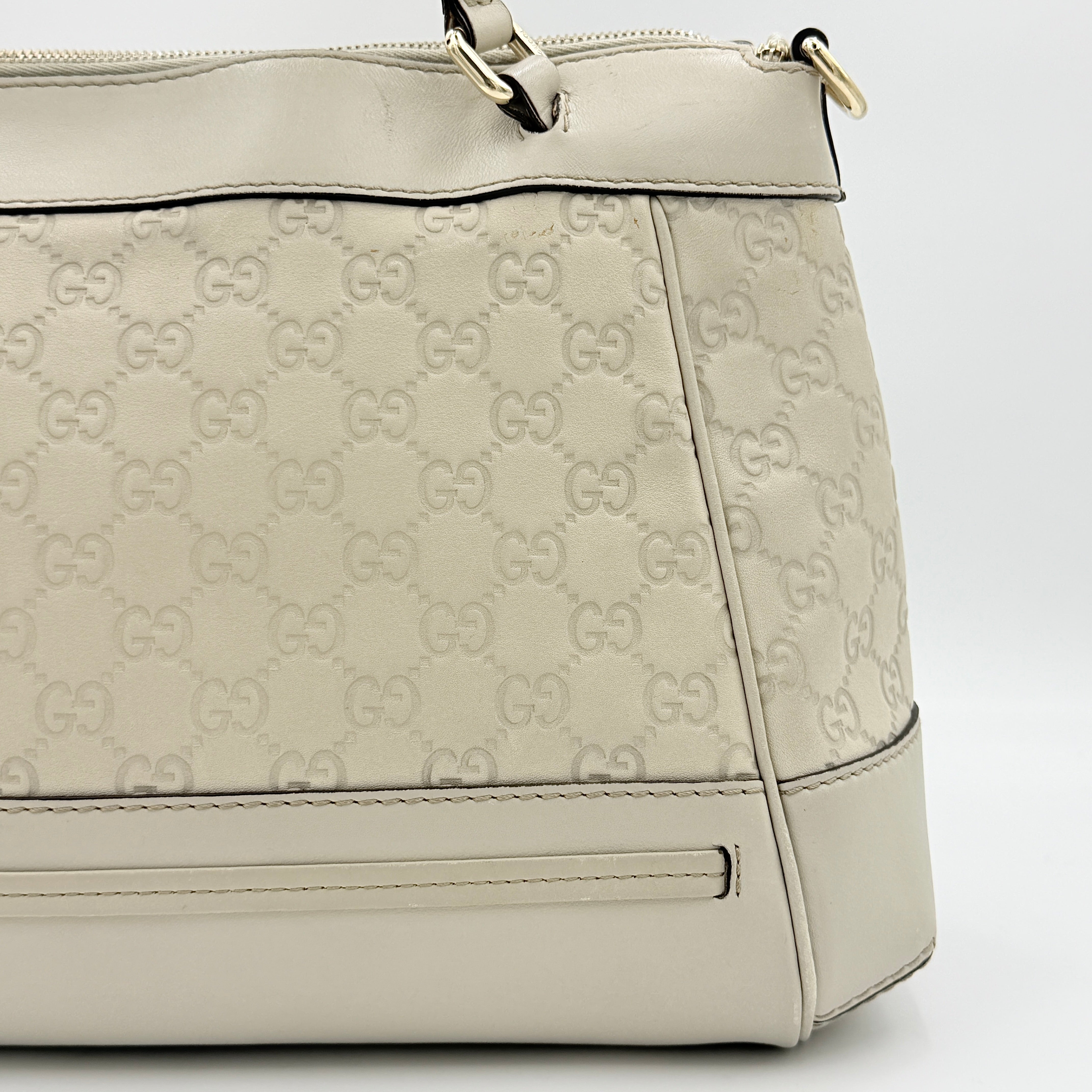 Gucci Mayfair Bow 2Way shoulder bag in cream GG monogram leather with dual handles and detachable strap, styled against a neutral backdrop.