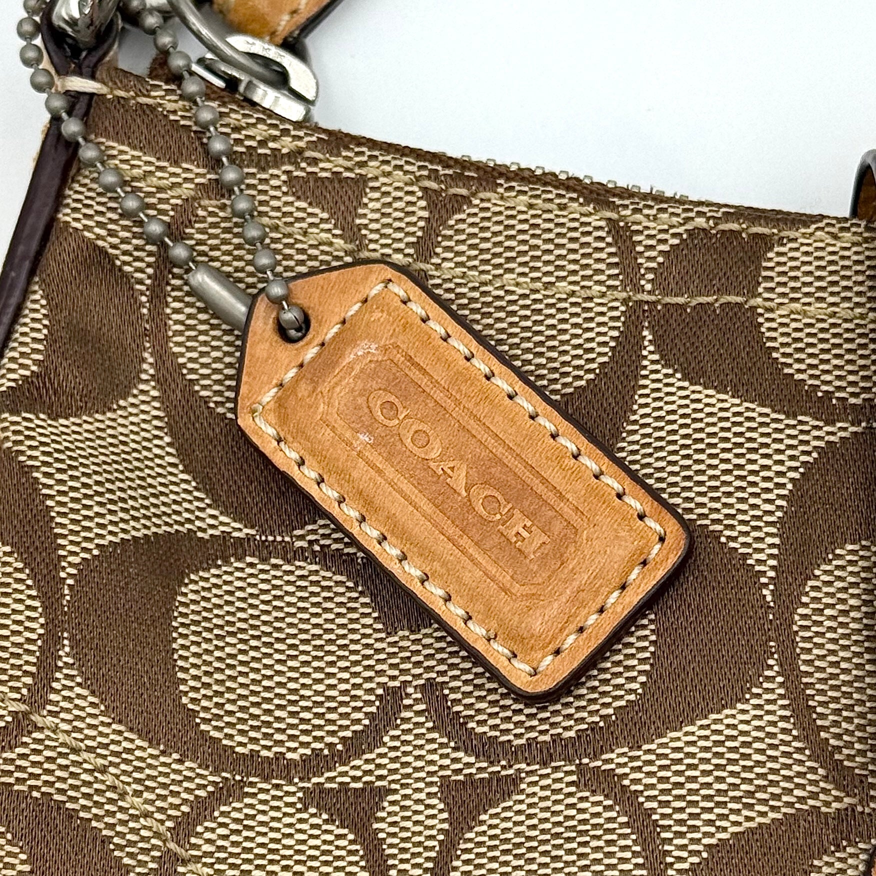 Coach Soho Demi shoulder bag in beige and tan monogram canvas with leather trim and buckle detail.