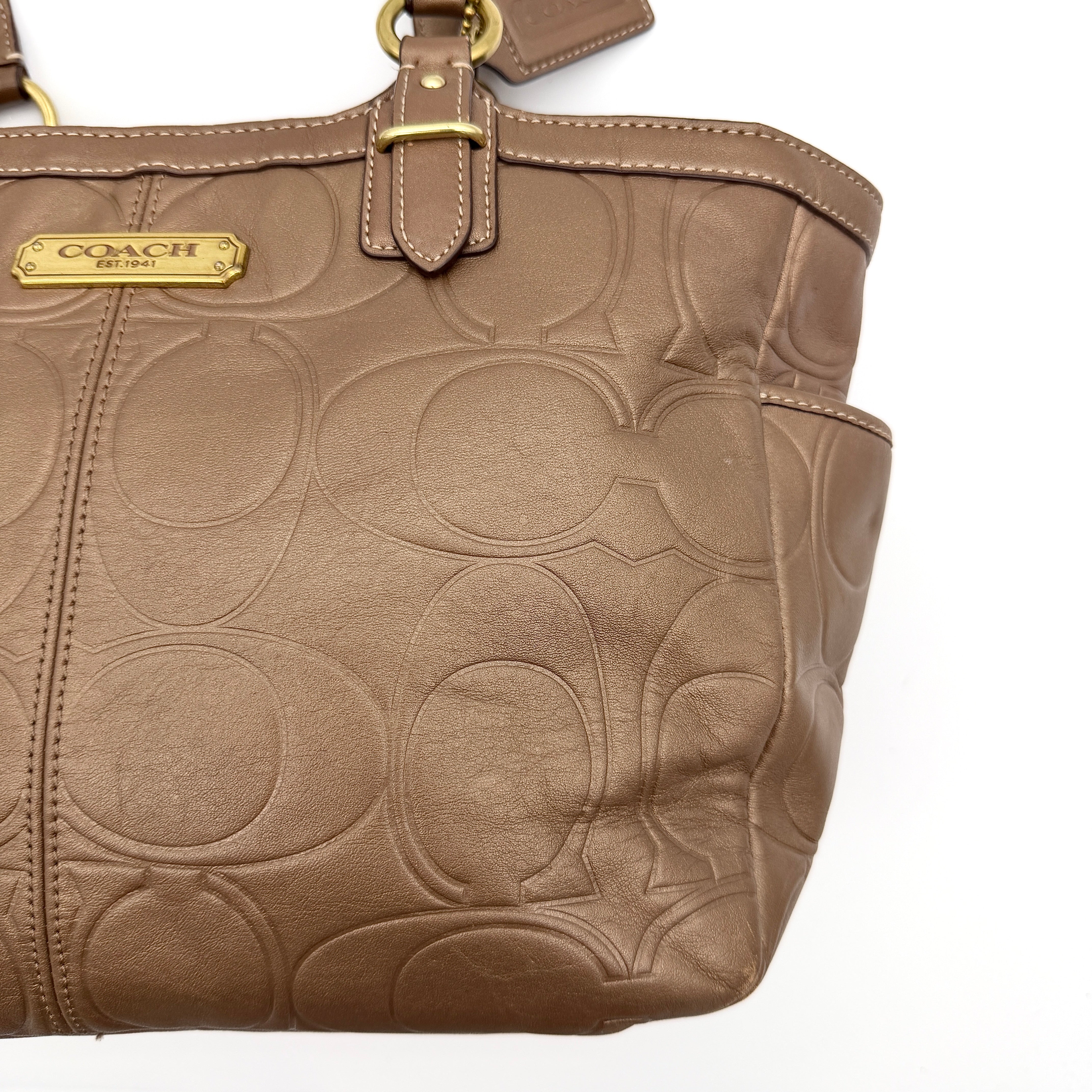 Coach Signature Gallery embossed leather tote bag in brown with gold tone hardware and dual handles.