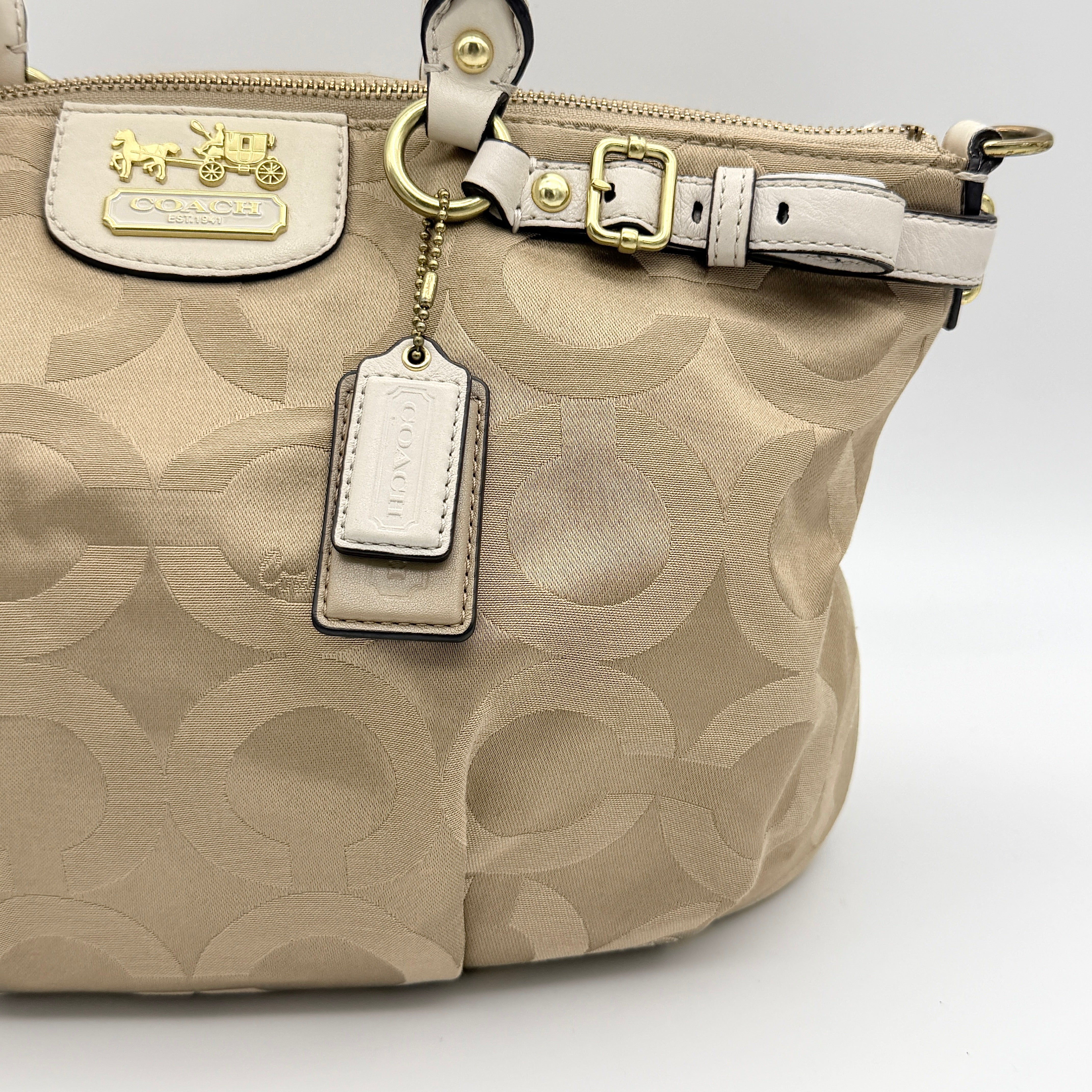 Beige Coach Madison Op Art Sophia shoulder bag with ivory leather handles, gold hardware, and detachable strap.