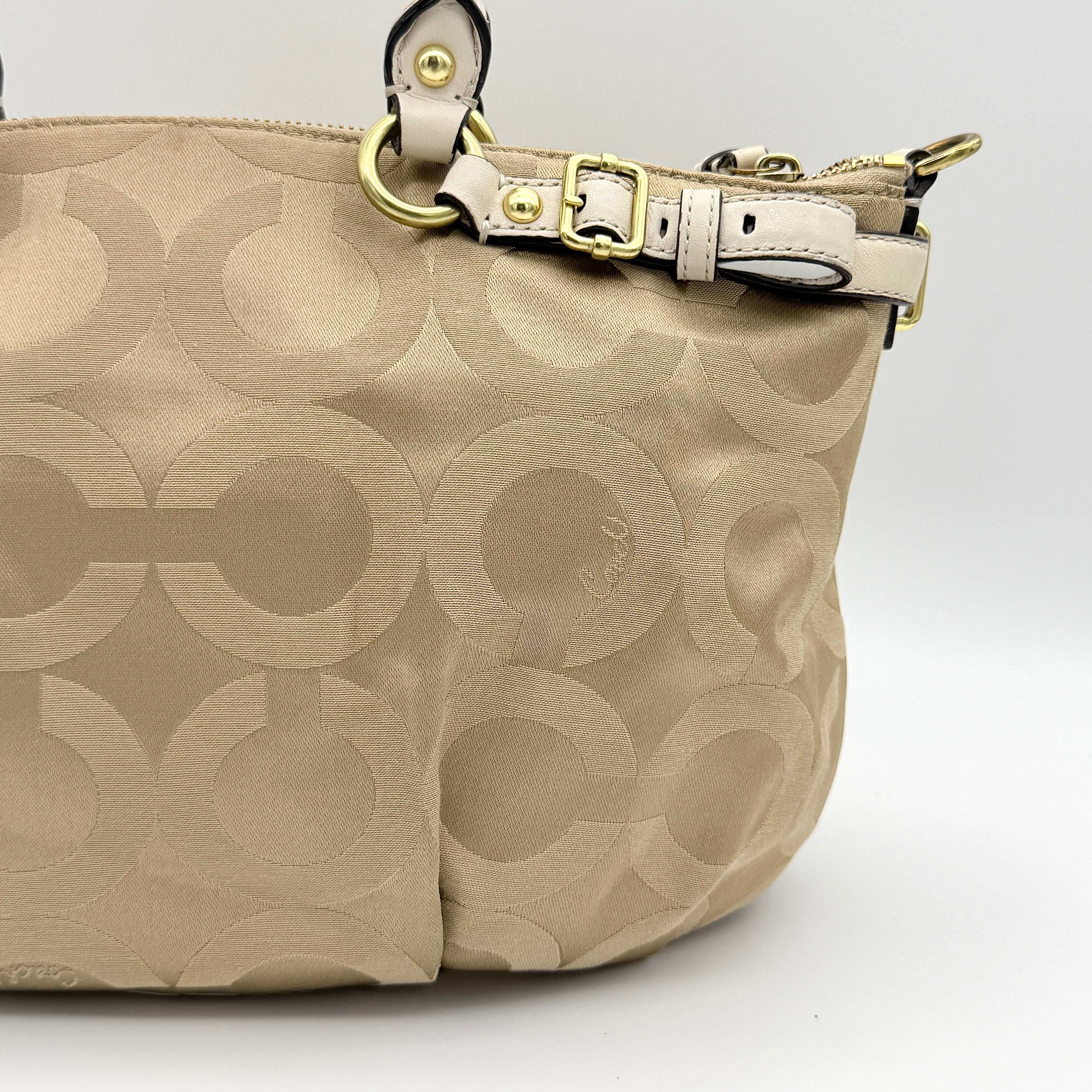 Beige Coach Madison Op Art Sophia shoulder bag with ivory leather handles, gold hardware, and detachable strap.