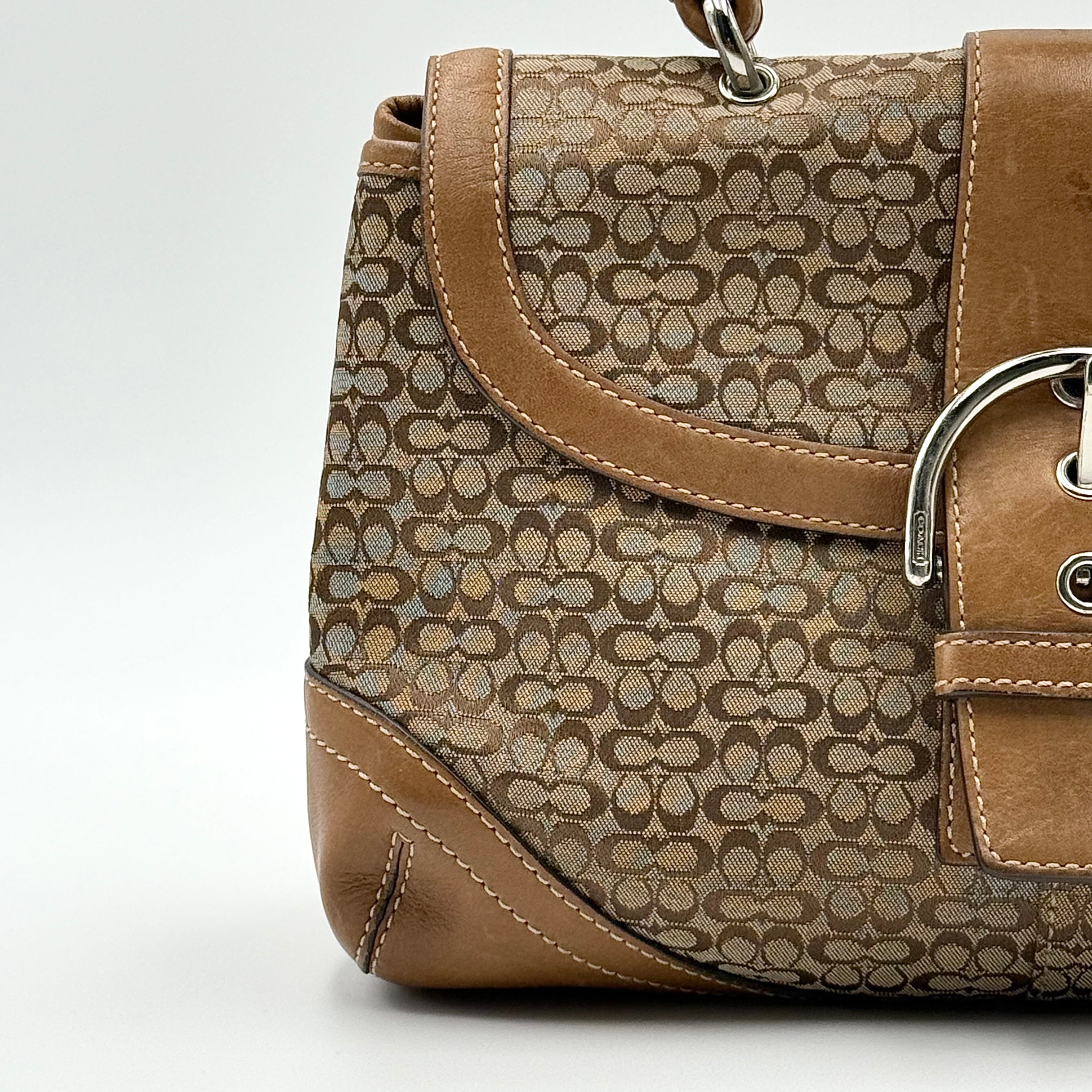 Coach Signature Soho shoulder bag in beige and tan jacquard with leather trim and silver D-ring buckle, shown against a white background.