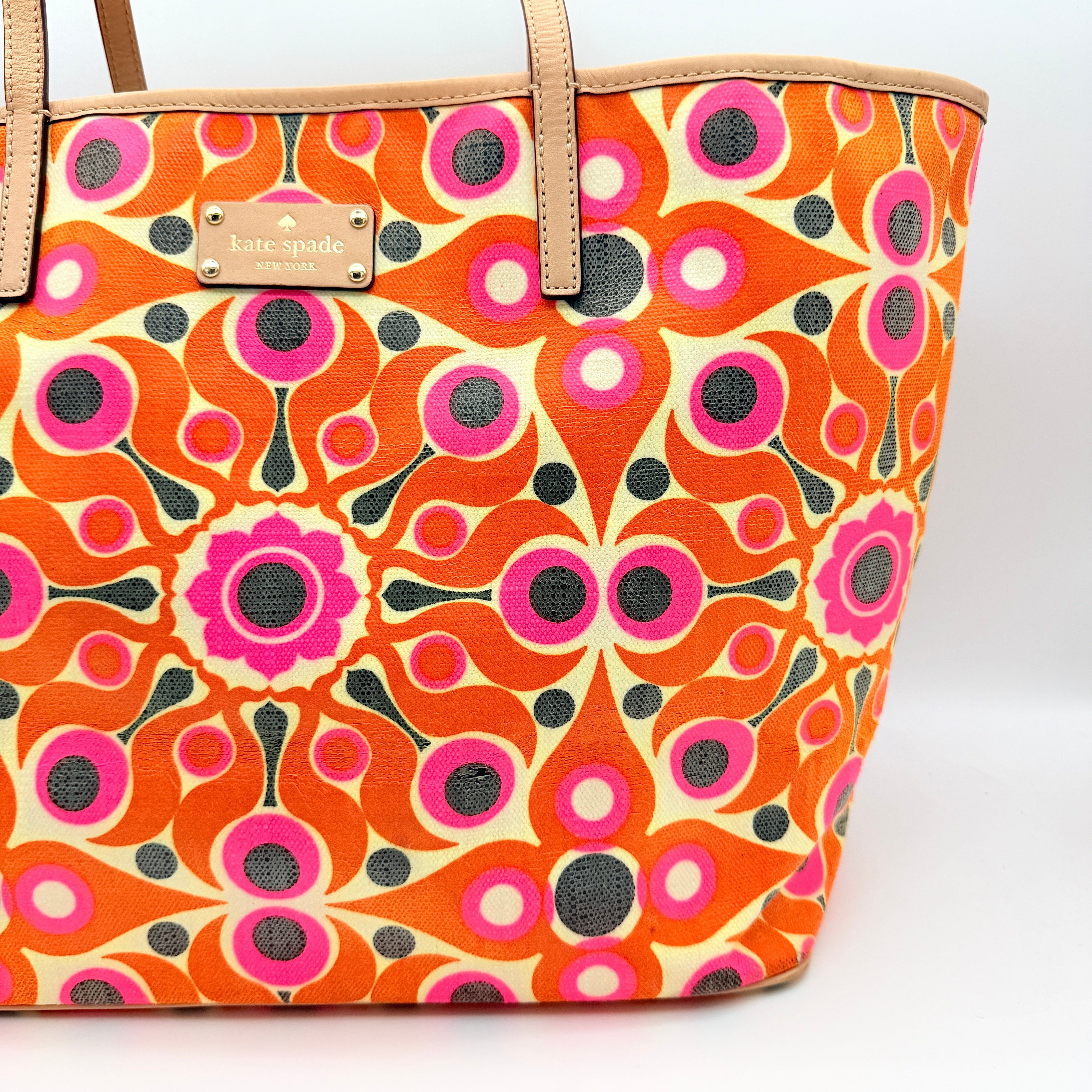 Kate Spade New York tote bag in a bold multicolour geometric pattern with beige leather handles, displayed upright against a white background.