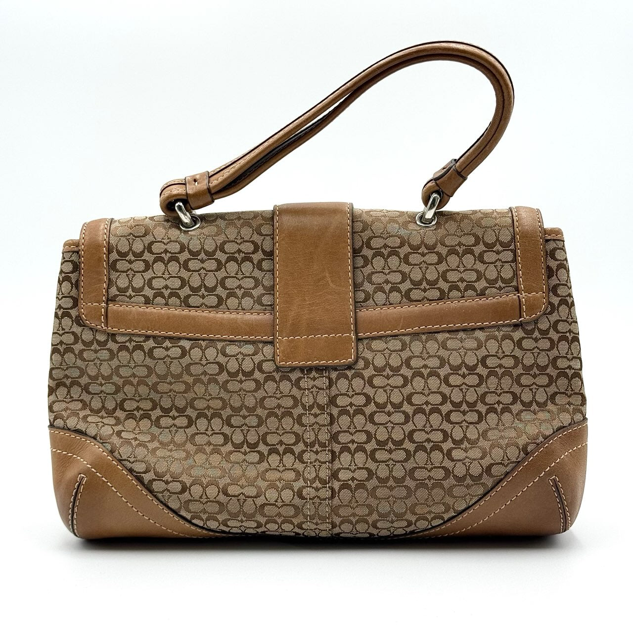 Coach Signature Soho shoulder bag in beige and tan jacquard with leather trim and silver D-ring buckle, shown against a white background.