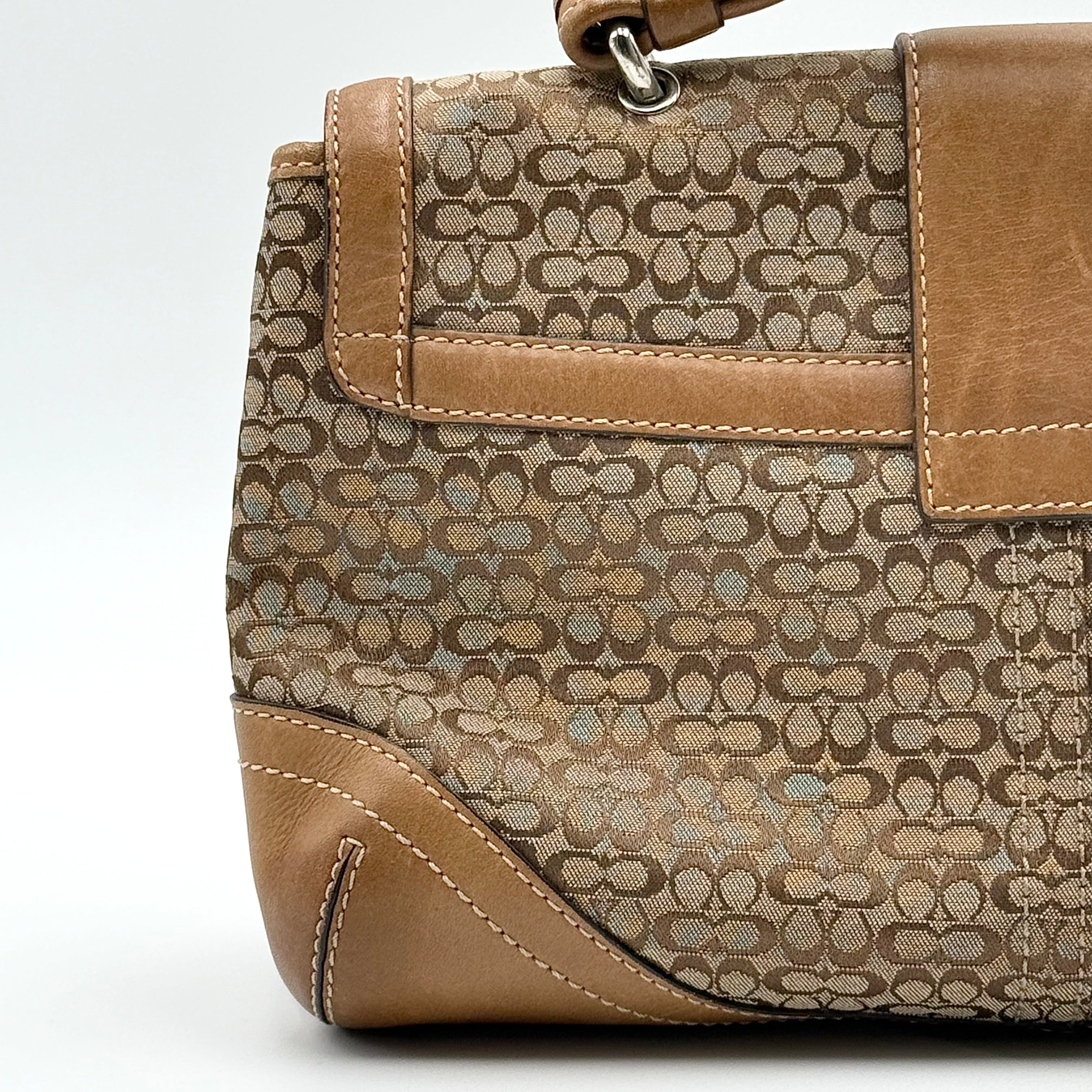 Coach Signature Soho shoulder bag in beige and tan jacquard with leather trim and silver D-ring buckle, shown against a white background.