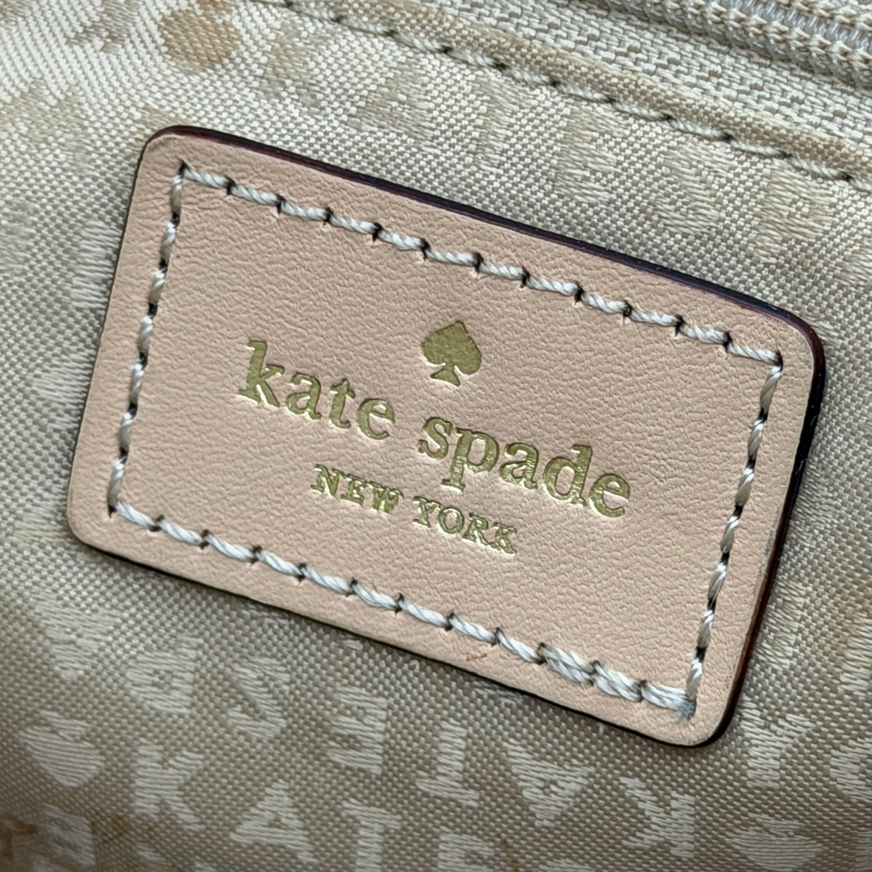 Kate Spade New York tote bag in a bold multicolour geometric pattern with beige leather handles, displayed upright against a white background.