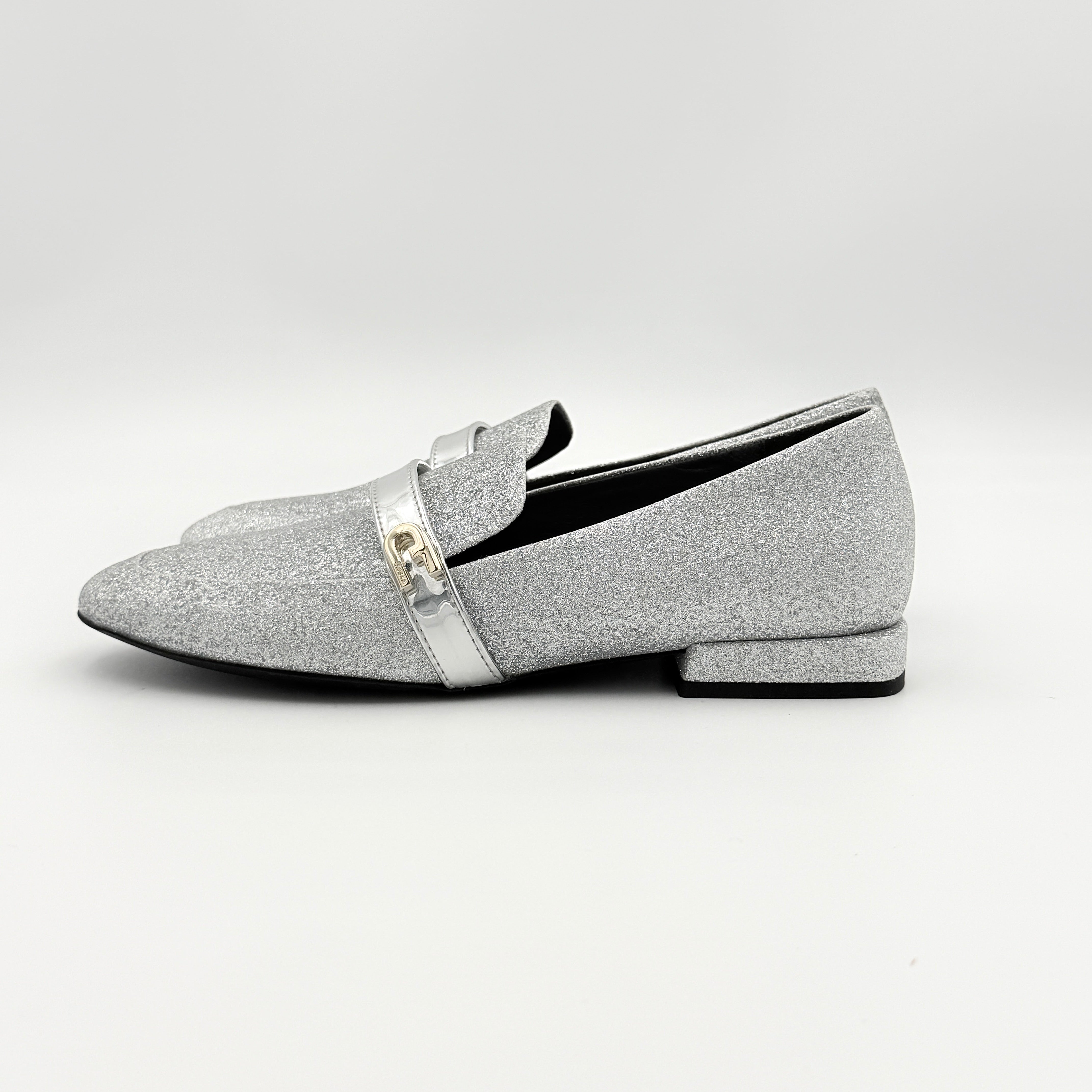 Furla 1927 T.20 loafers in silver microglitter with metallic strap and gold-tone detail, displayed in a three-quarter view.