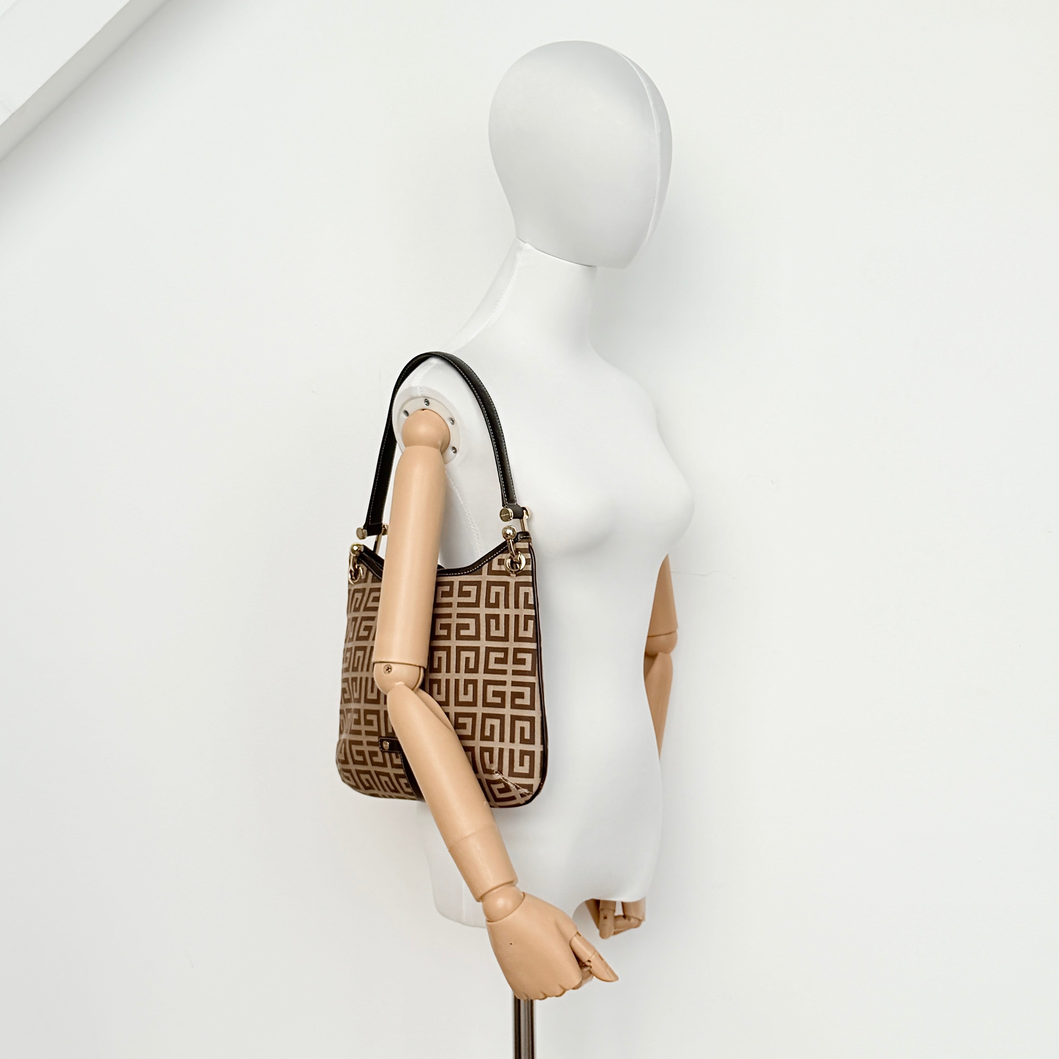 The Givenchy Monogram Hobo Shoulder Bag in brown canvas with black leather trim and gold hardware, displayed front-facing.