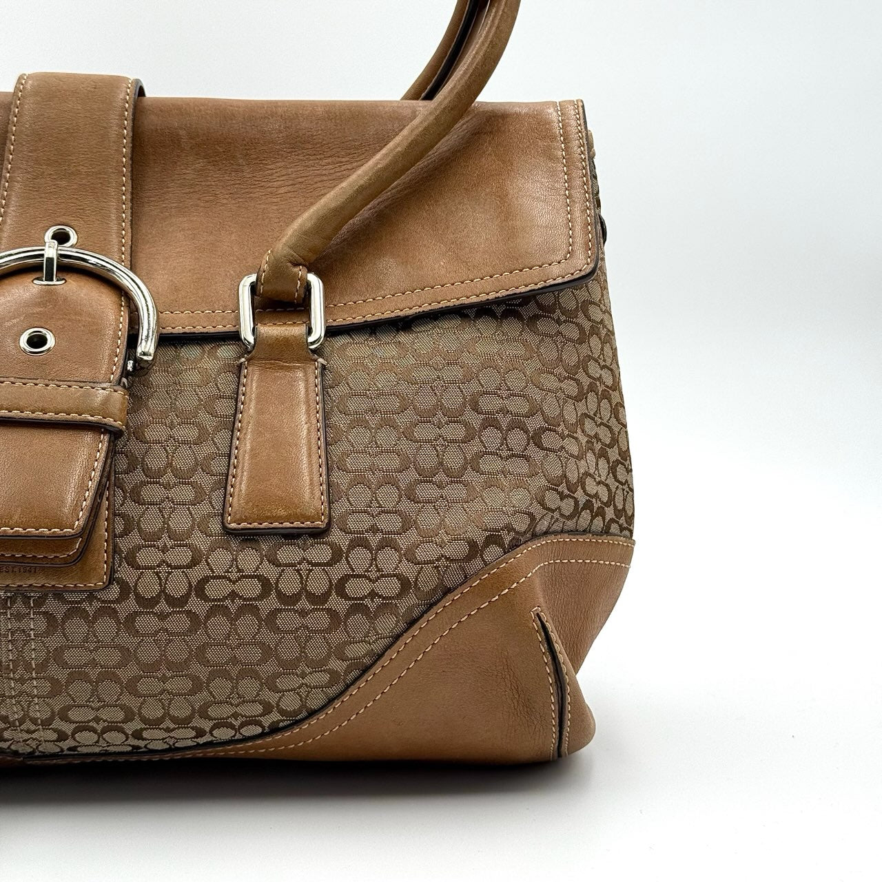 Coach Signature Soho shoulder bag in beige and tan canvas with leather trim and silver buckle.