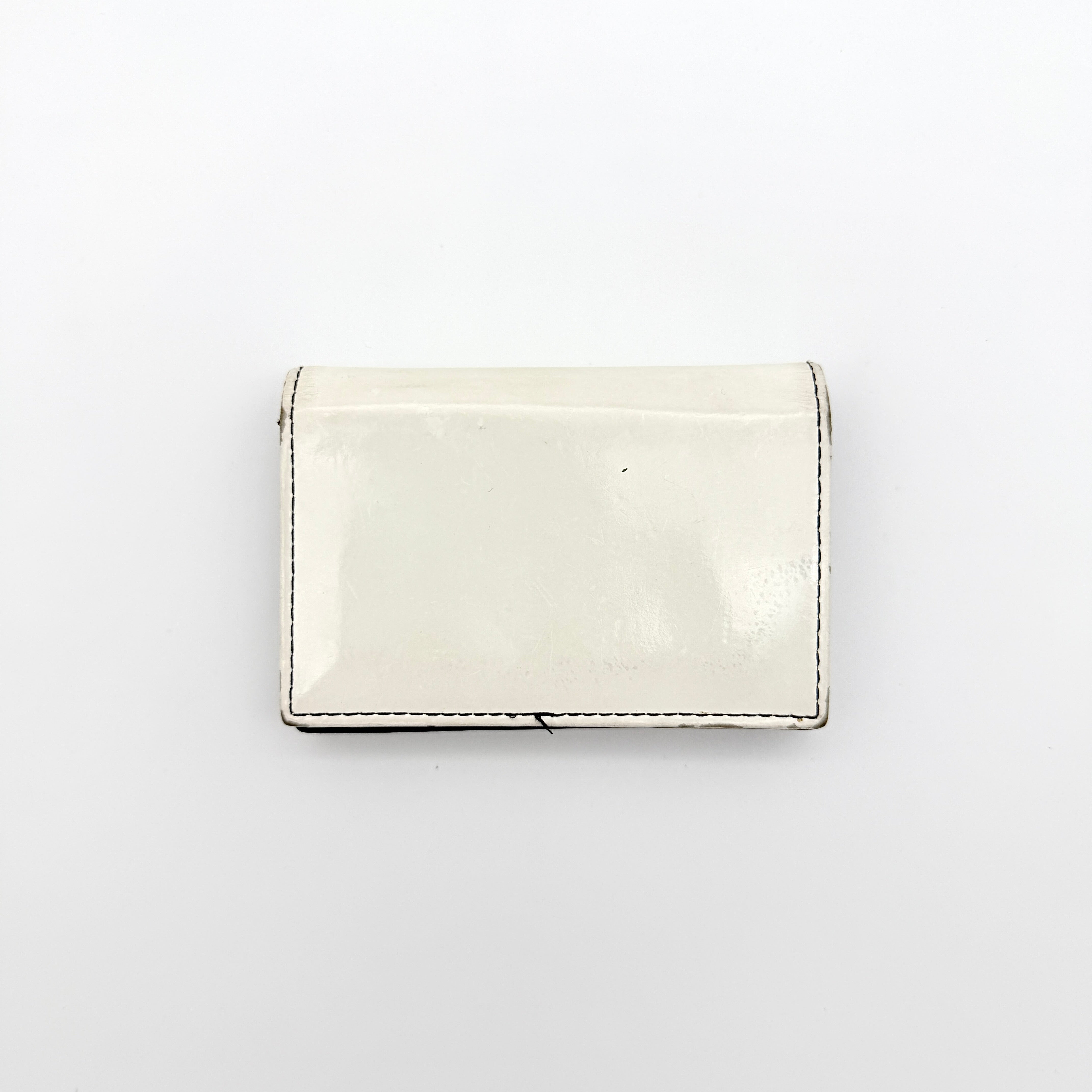 Diesel card case in white leather with bold black grommets and studs on the front.