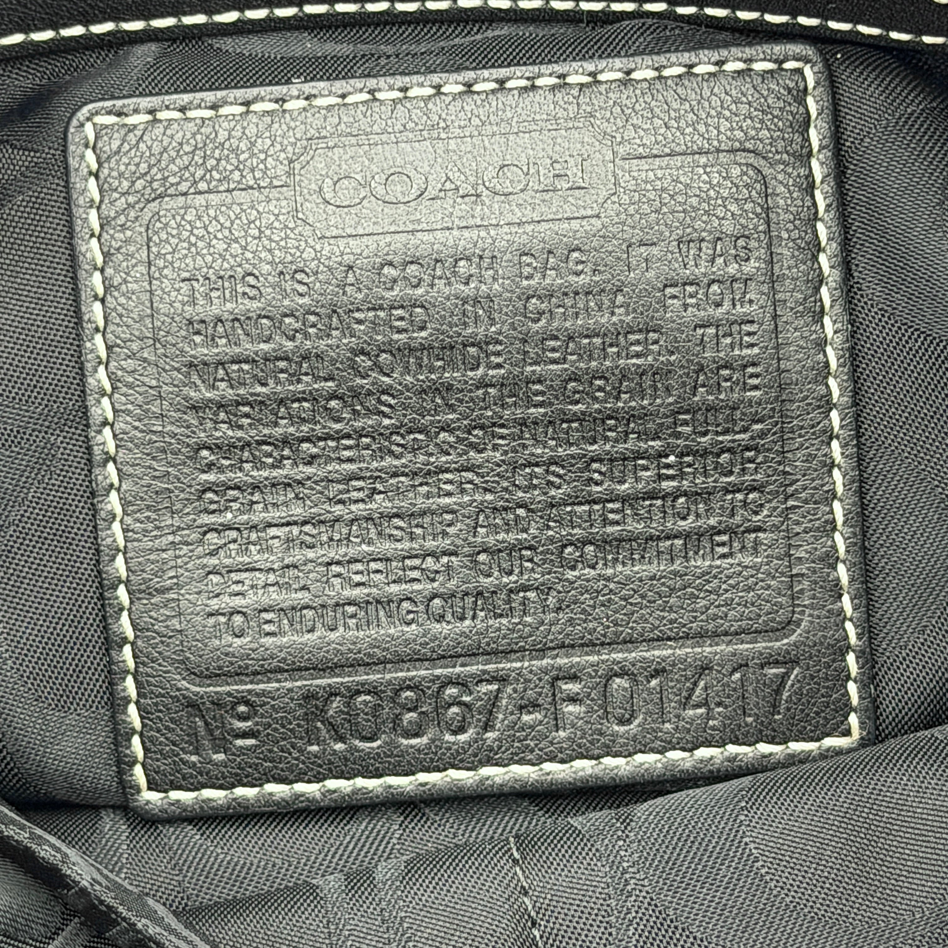 Coach Signature East West Shoulder Bag in black leather with silver hardware and contrast stitching, displayed on a white background.