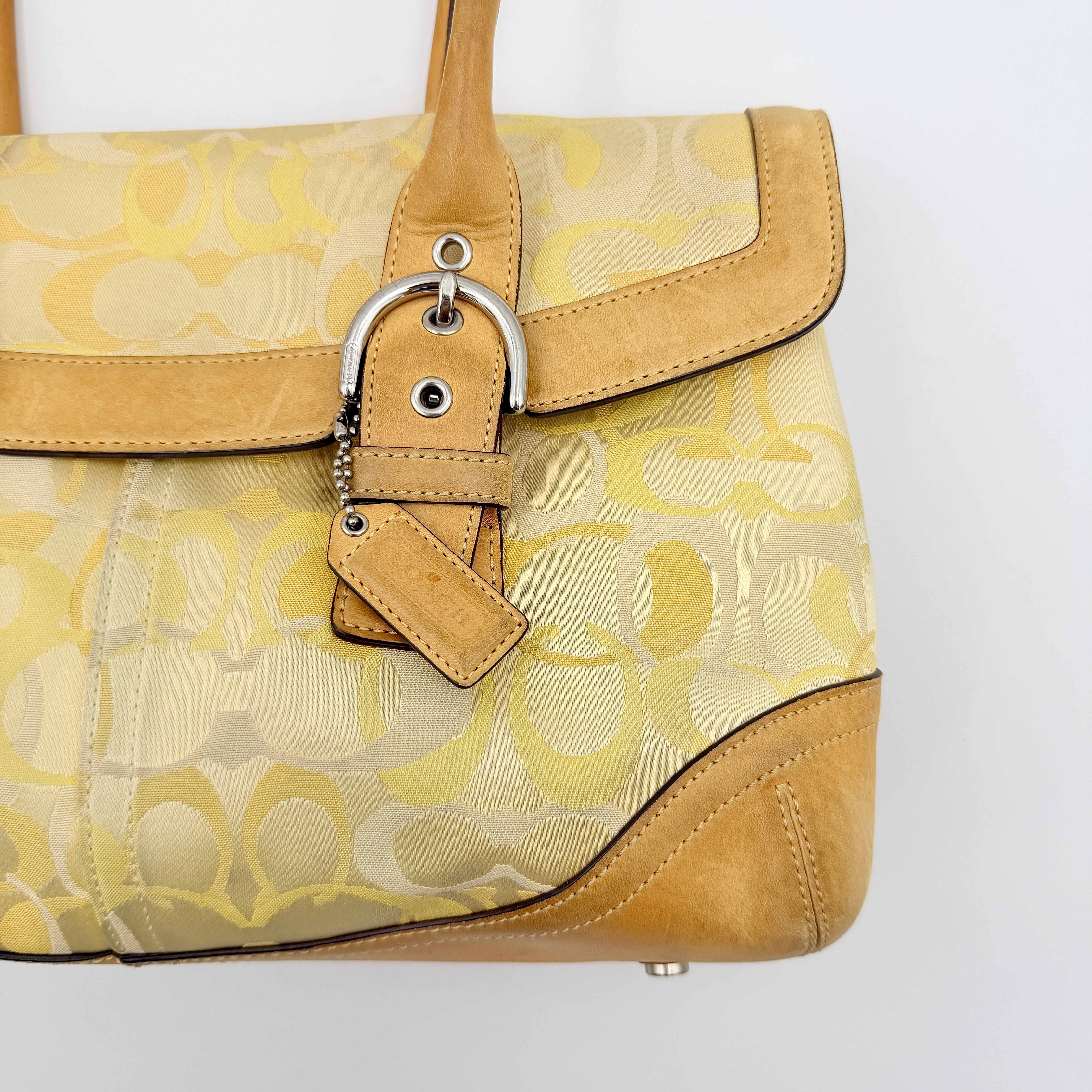 Coach Soho shoulder bag in yellow signature optic fabric with tan leather trim and silver hardware, shown with double handles.